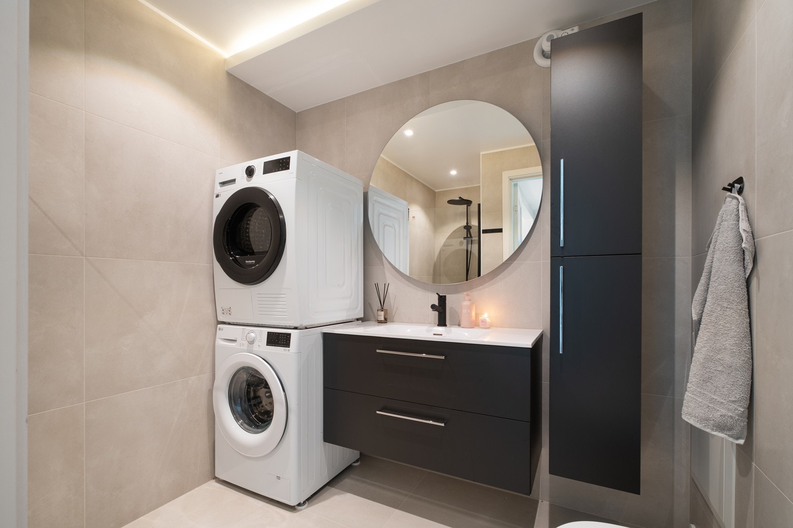 Badet er smakfullt innredet med mørke, glatte fronter, heldekkende servant og både under- og høyskap. Opplegg til vask og tørk. Galleribilde