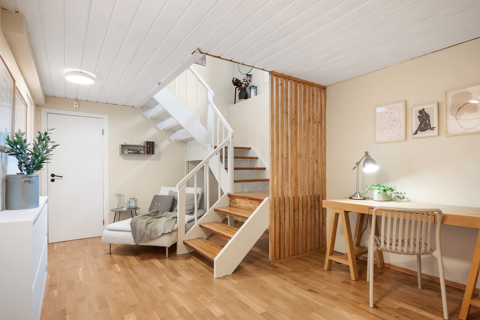 Underetasjen imponerer med en stilren hvit trapp og en elegant spilevegg i tre, som gir rommet et moderne preg Galleribilde