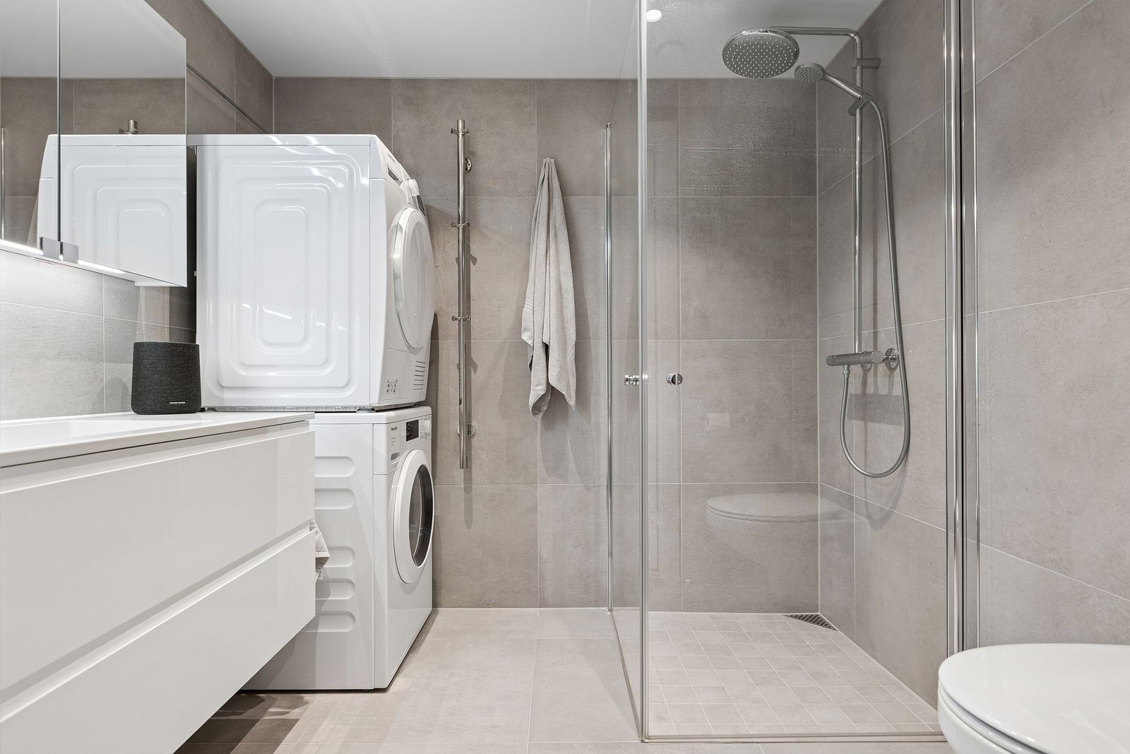 Moderne og flislagt baderom med varme i gulv og opplegg til vaskemaskin. Det medfølger en Miele kombimaskin. Galleribilde