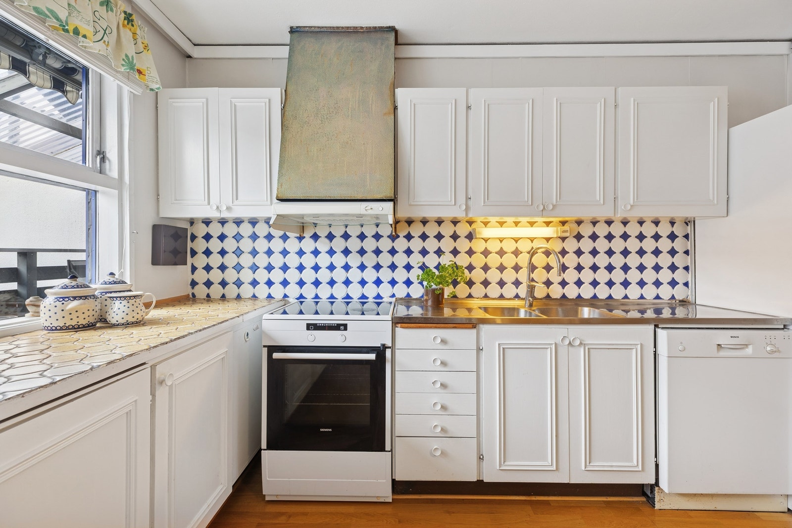 Kjøkkeninnredning med profilerte fronter og benkeplate av rustfritt stål med nedfelt oppvaskkum. Galleribilde