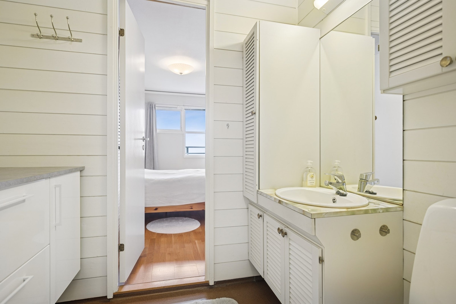 Baderom fra byggeår. Bestående vegghengt servantinnredning med dører og ovenpåliggende servant, samt gulvstående toalett. Galleribilde