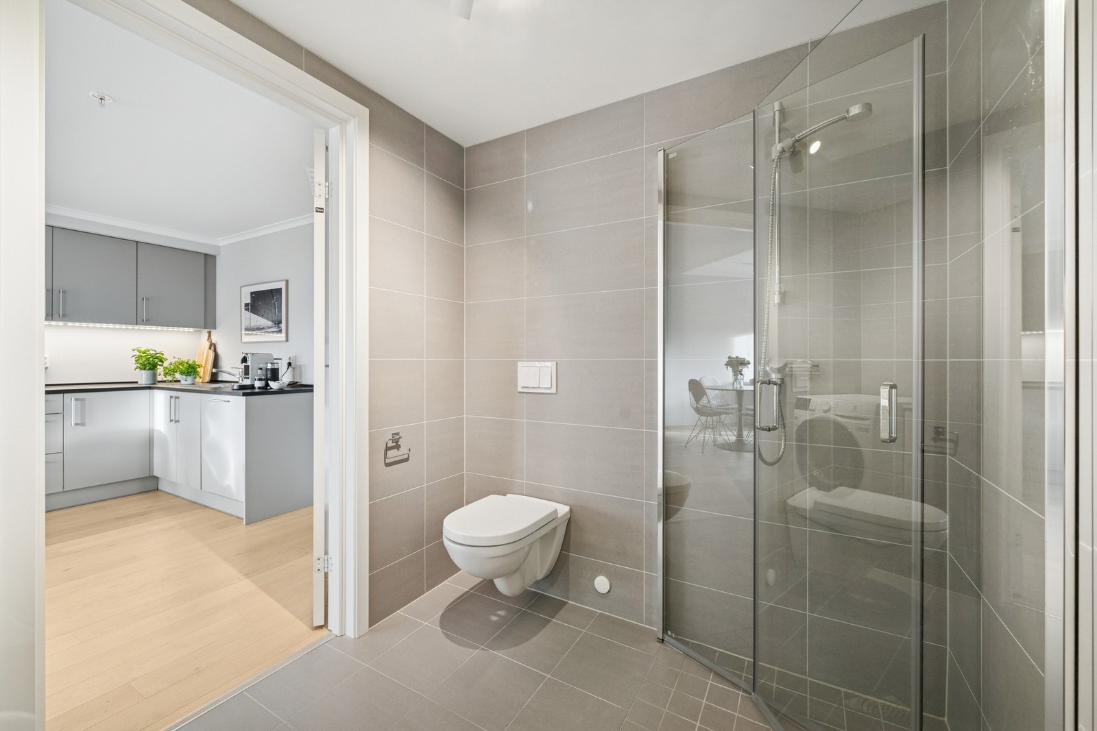 Badet har en lun, moderne stil med sandfargede fliser på vegger og gulv. Galleribilde