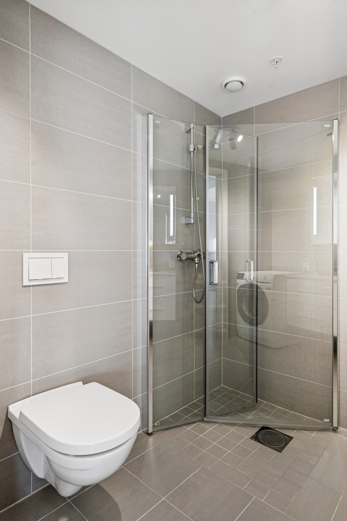 I nedsenket dusjhjørne er det mindre fliser på gulvet, rette, innfellbare glassdører og dusjgarnityr montert på vegg. Galleribilde