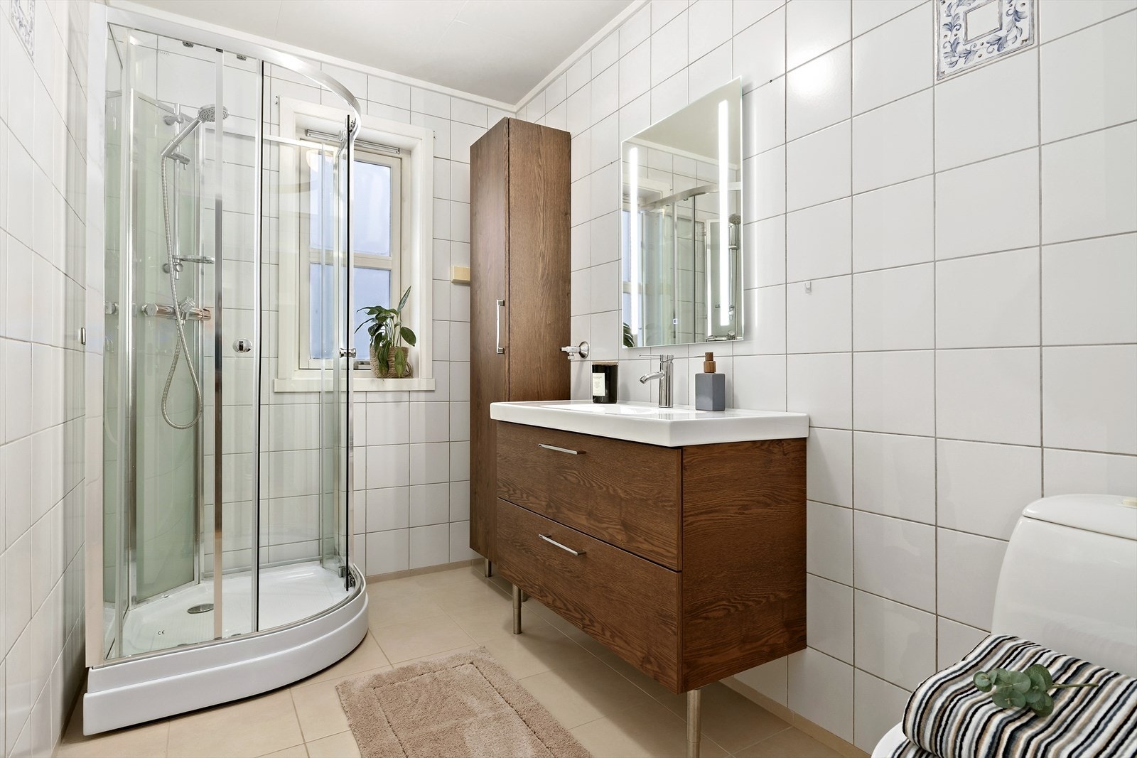 Badet er flislagt og har termostatstyrte elektriske varmekabler. Det har baderomsinnredning i mørk eik med nedfelt servant og moderne speil med touch-sensor. Galleribilde