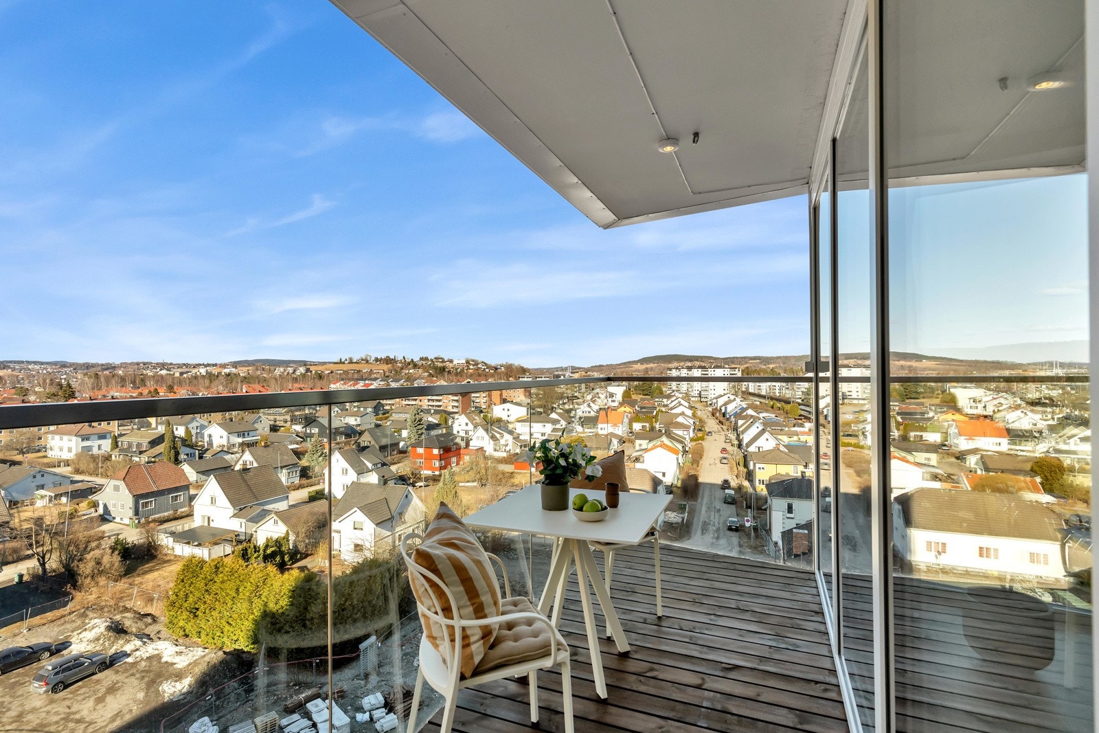 I forlengelse av stuen/kjøkkenet har leiligheten en balkong med glassrekkverk og utelys, innrammet med stilige, hvite detaljer. Med overbygg kan man nyte utedagene til det fulle. Galleribilde