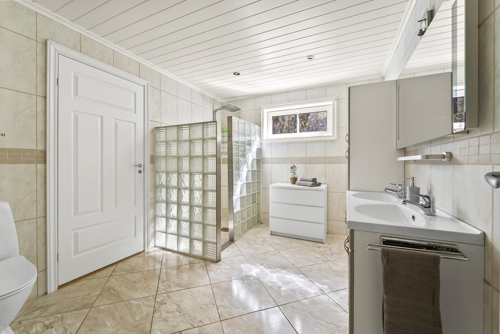 Fliselagt bad i 1. etasje med inngang til vaskerom og videre adkomst til garasje. Badet er innredet med baderomsinnredning, toalett og dusjløsning. Galleribilde