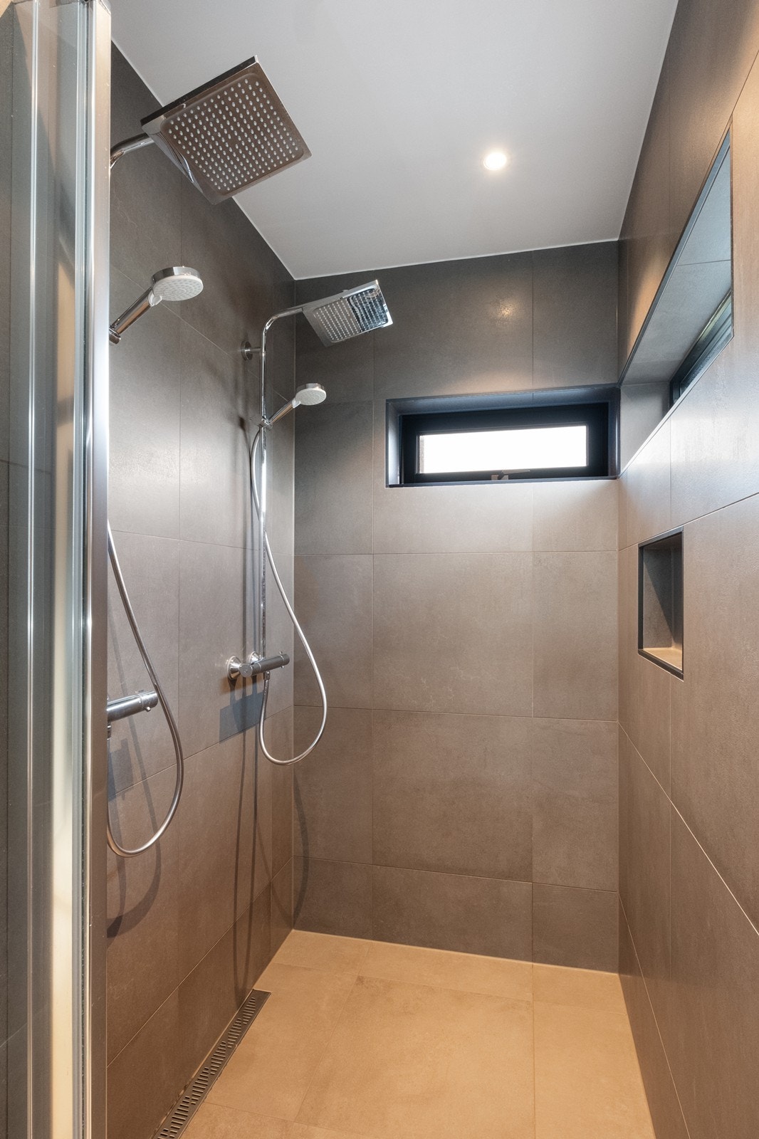 Stor dusjnisje med glassdør og dobbel tropedusj. Galleribilde