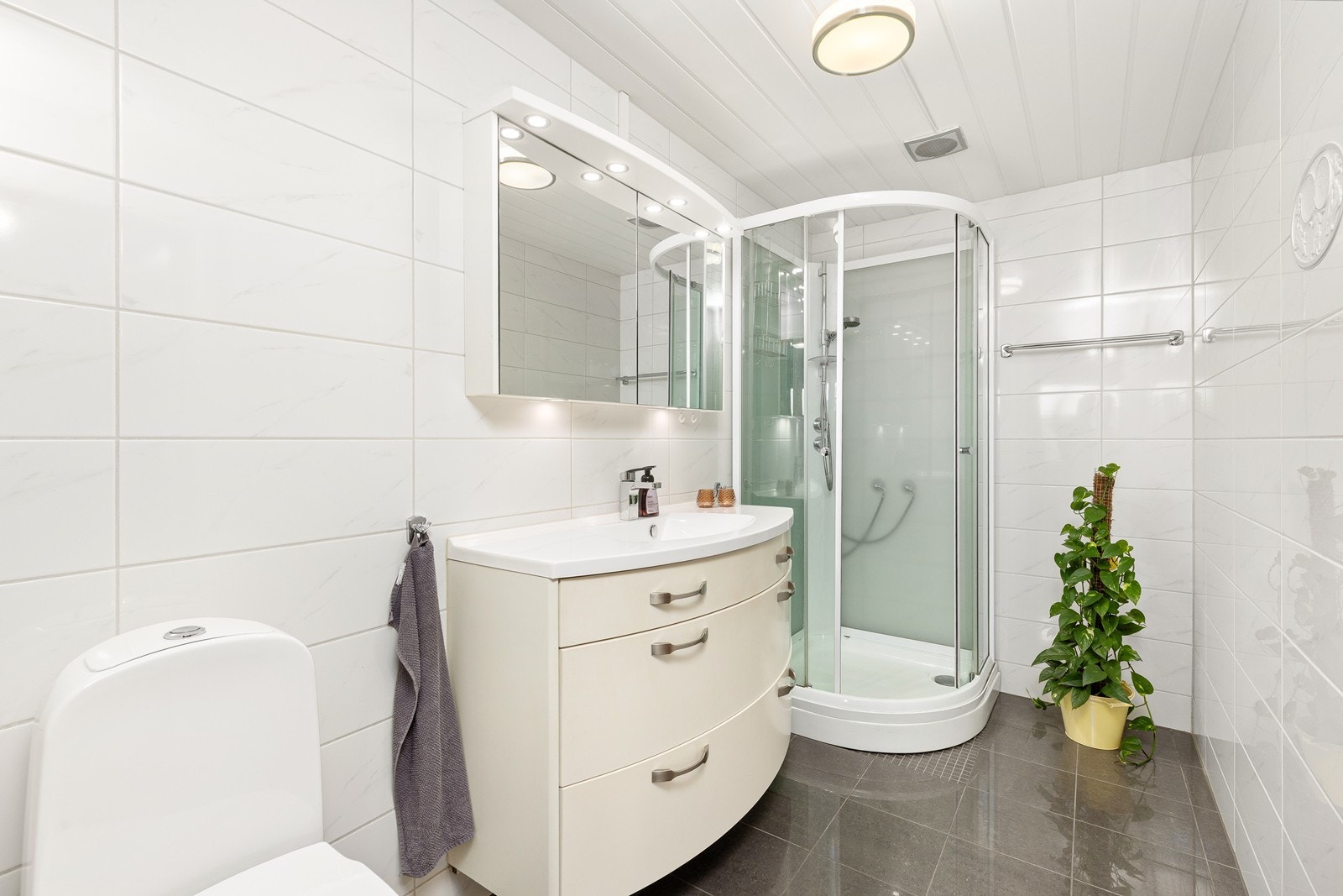 Badet er flislagt med elektriske varmekabler og er utstyrt med innredning med nedfelt servant, toalett og dusjkabinett. Galleribilde