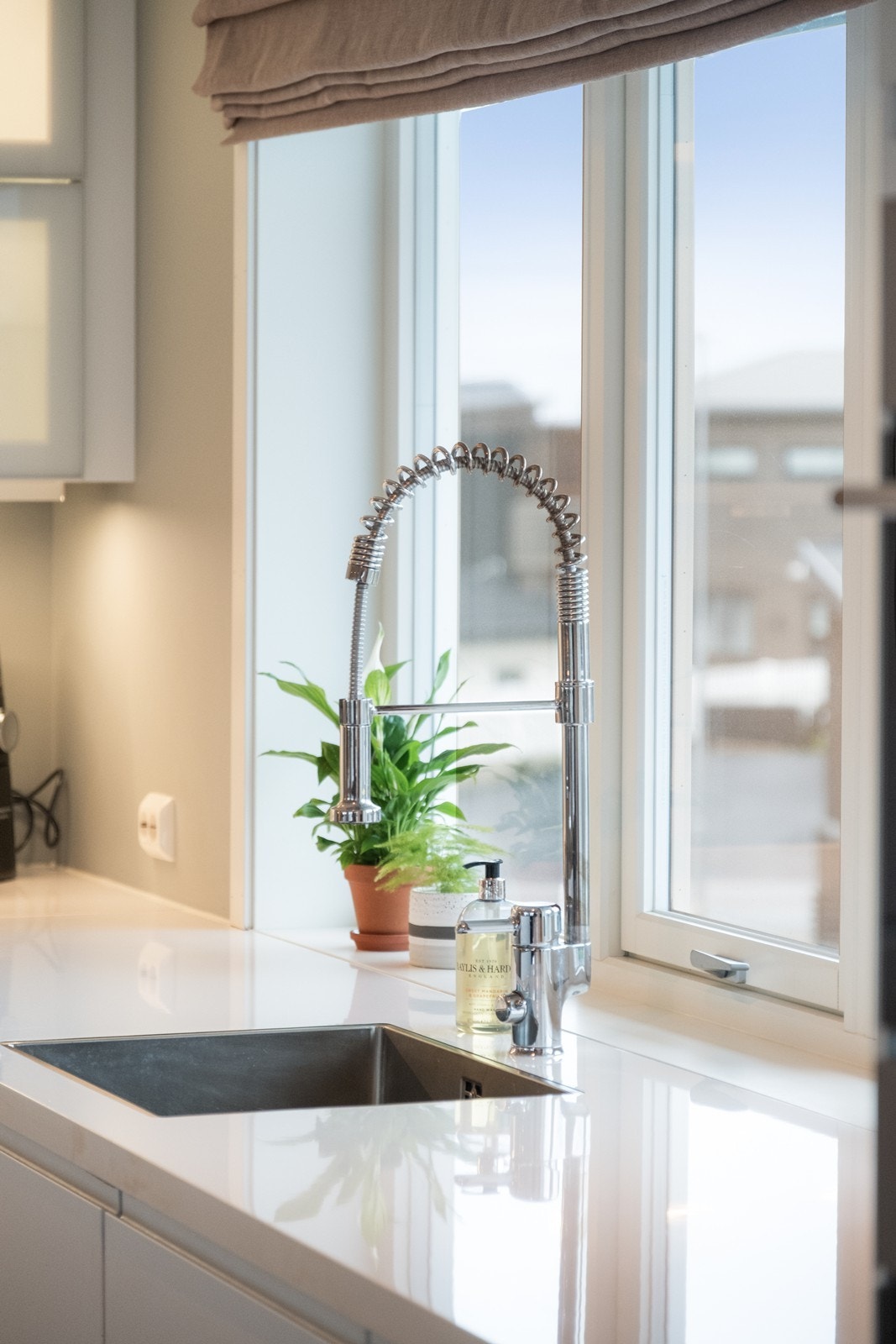 Kjøkkenet har stilren vask og praktisk armatur ved arbeidsbenken. Galleribilde