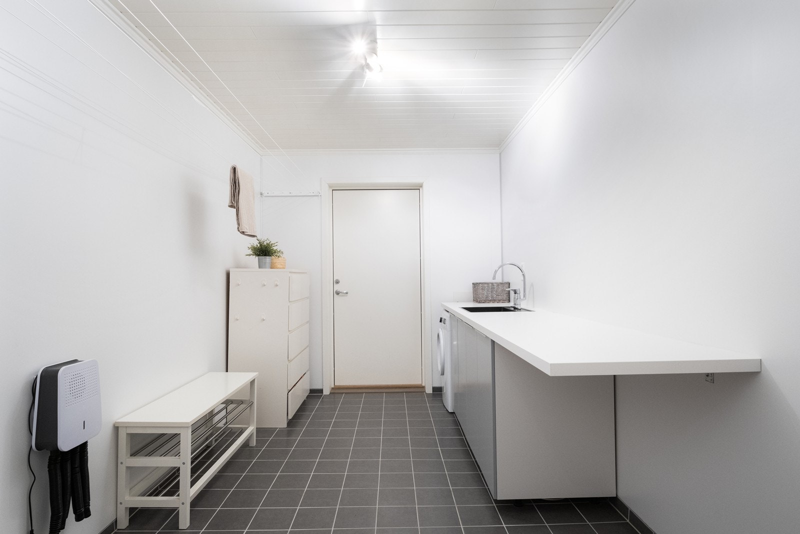 Flislagt gulv med varmekabler gir et komfortabelt og praktisk vaskerom. Rommet er utstyrt med laminat benkeplate, underskap og utslagsvask. Galleribilde