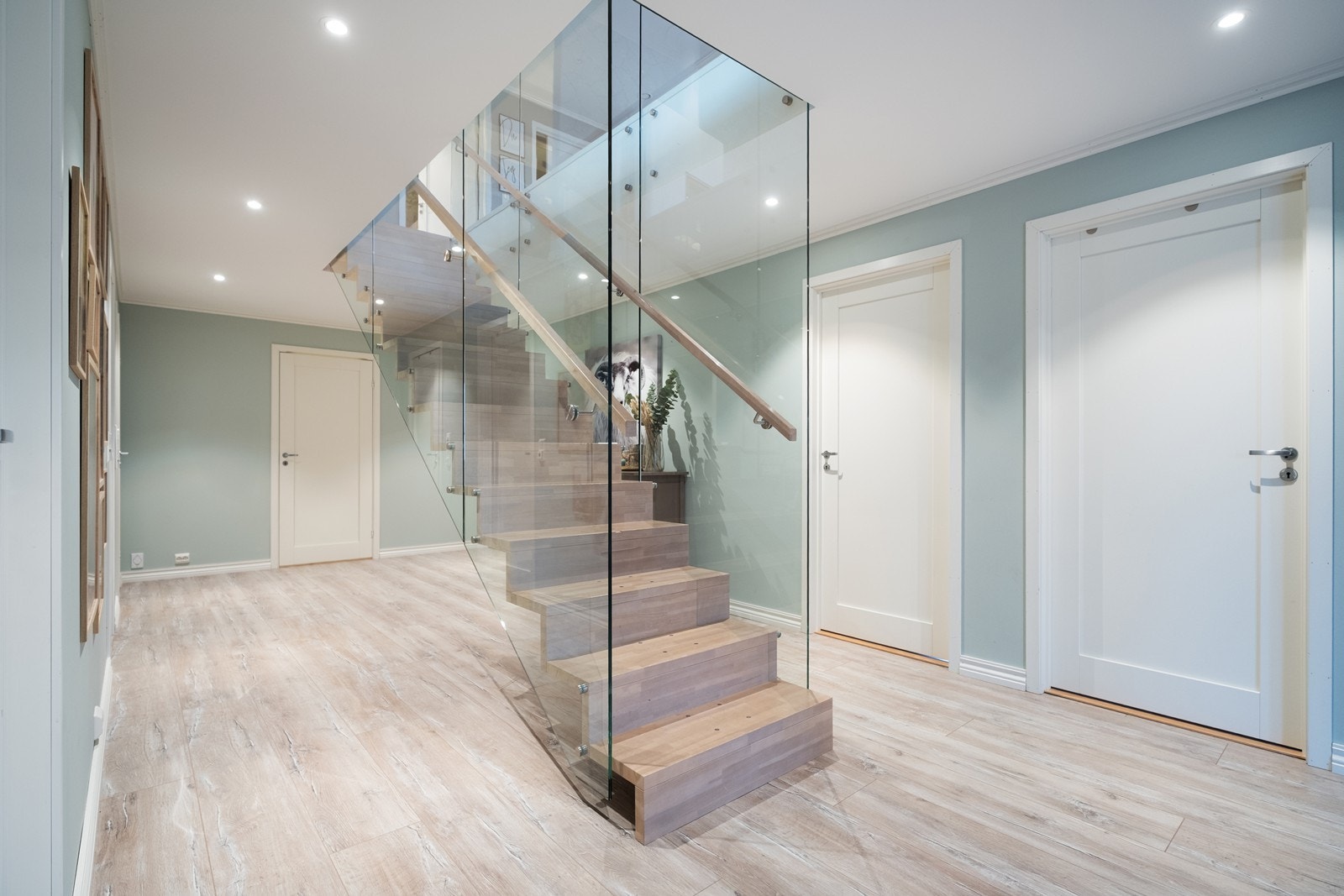 Trappen mellom etasjene er utført i heltre med glassrekkverk, som gir et lett og luftig uttrykk. Galleribilde