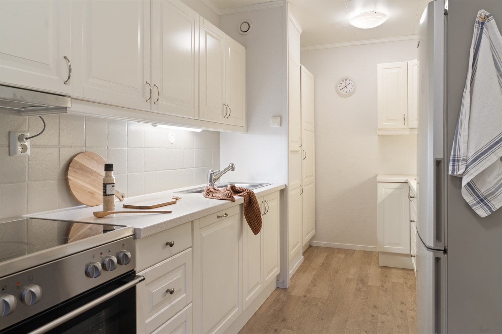 De klassiske profilerte frontene kombinert med lyse fliser og laminert benkeplate gir et rent og elegant uttrykk. Galleribilde