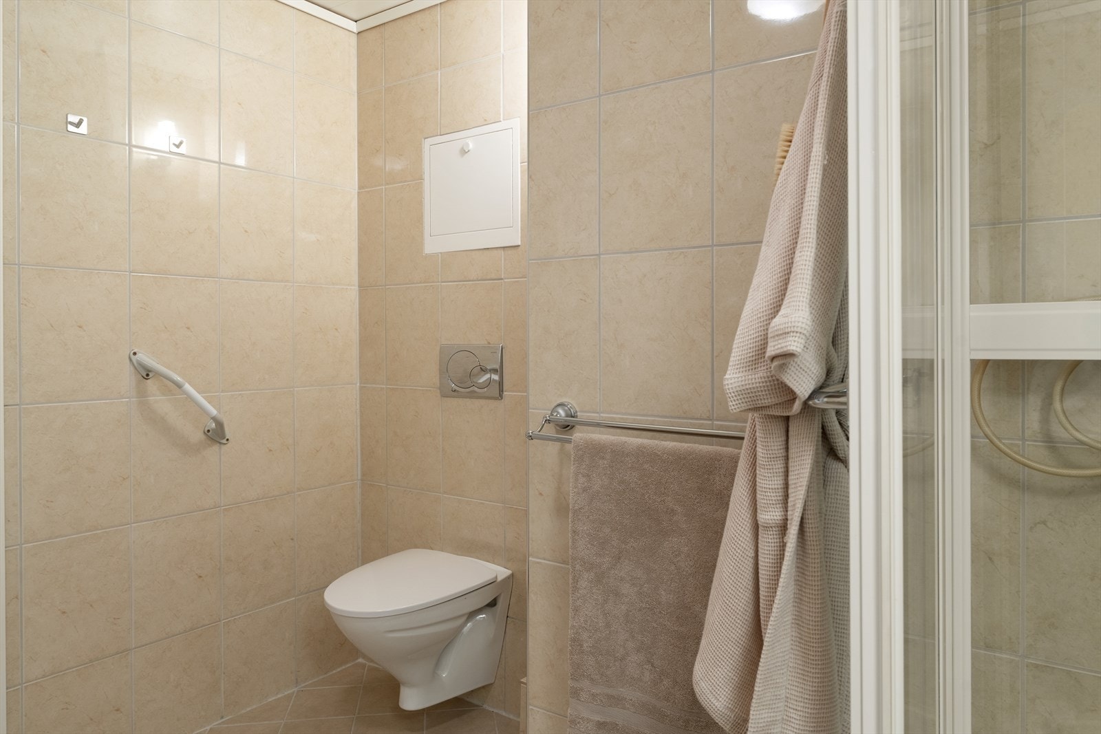 Separat toalett sone med flislagte overflater og vegghengt toalett. Galleribilde