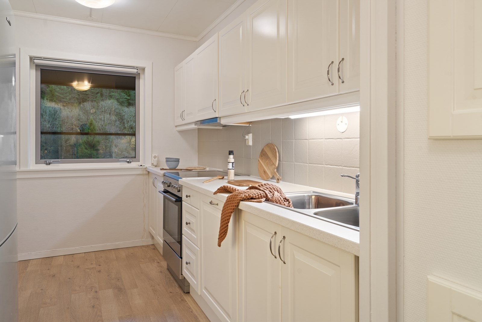 Et stort vindu gir naturlig lys og utsikt mot grøntområdet bak. Galleribilde