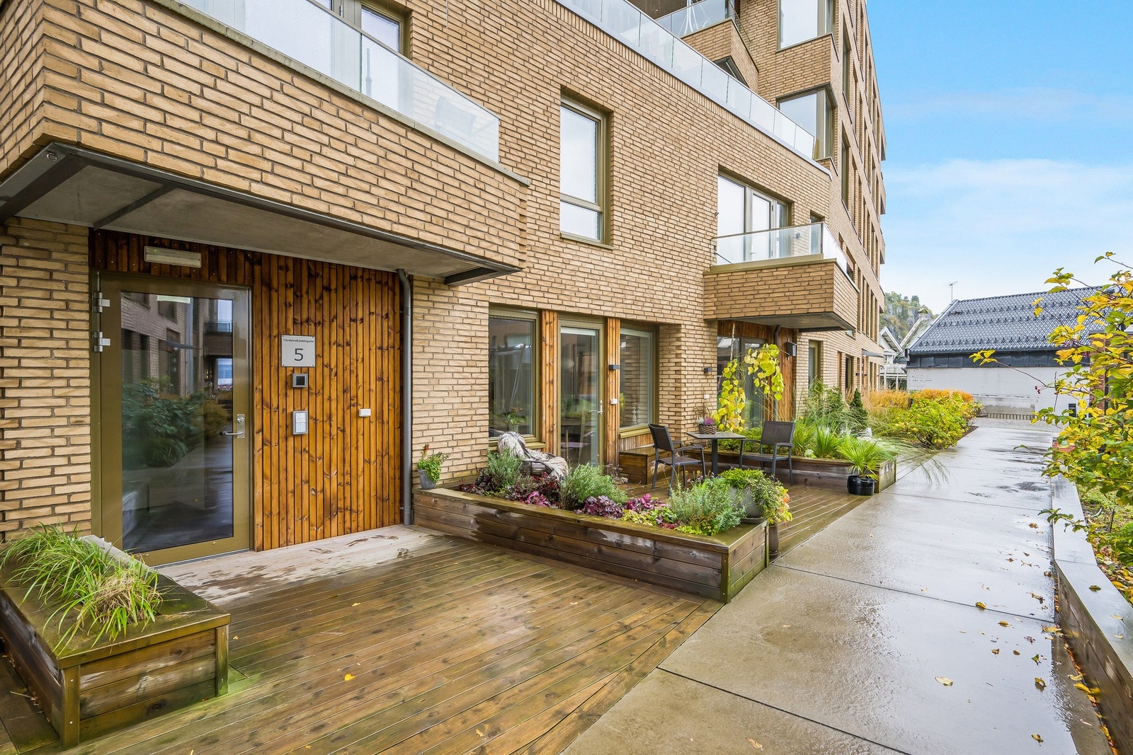 Leiligheten har en trivelig terrasse med utgang fra kjøkkenet. Til venstre i bildet ser vi også felles inngangsparti. Galleribilde