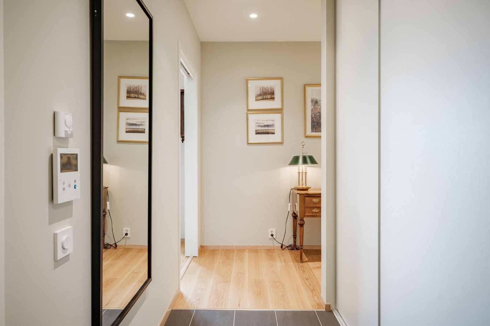 Lys og innbydende entré med flislagt gulv, gulvvarme, downlights og praktisk skyvedørsgarderobe. Galleribilde