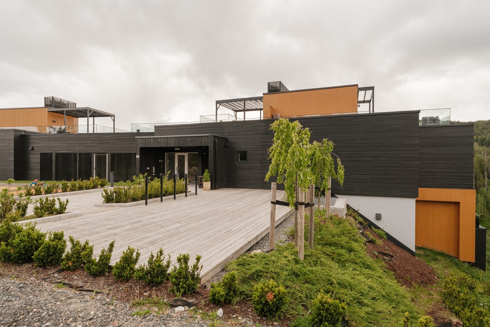 Tomten er pent opparbeidet med asfalterte internveier, parkeringsplasser, gressplen, prydbusker, trær og variert beplantning som skaper et grønt og innbydende bomiljø. Galleribilde