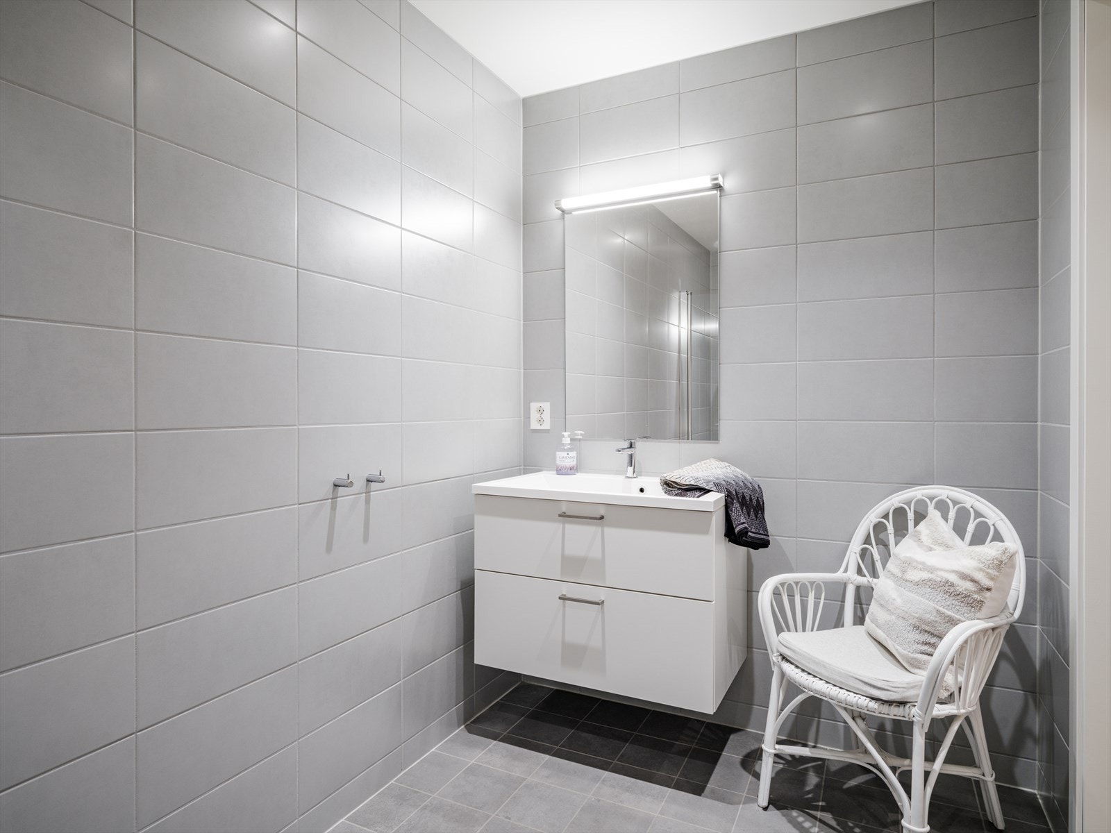 Rommet inneholder servantskap med nedfelt servant, speil med belysning, vegghengt toalett og dusjhjørne med innfellbare dusjdører i herdet glass Galleribilde