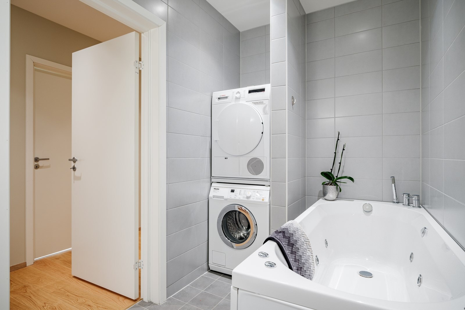 Romslig og delikat bad kombinert med vaskerom, oppført med fliser på gulv og vegger samt malt himling. Galleribilde