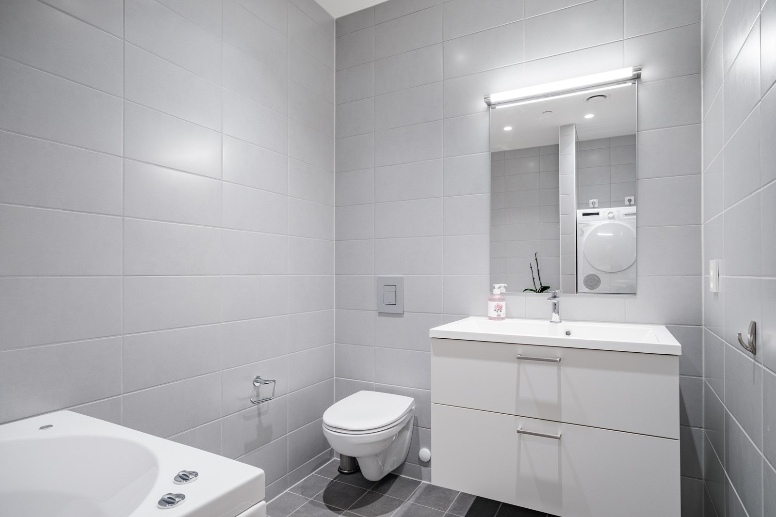 Rommet er utstyrt med servantskap med nedfelt servant, speil med belysning, vegghengt toalett med innebygd sisterne og frittstående boblebadekar. Galleribilde