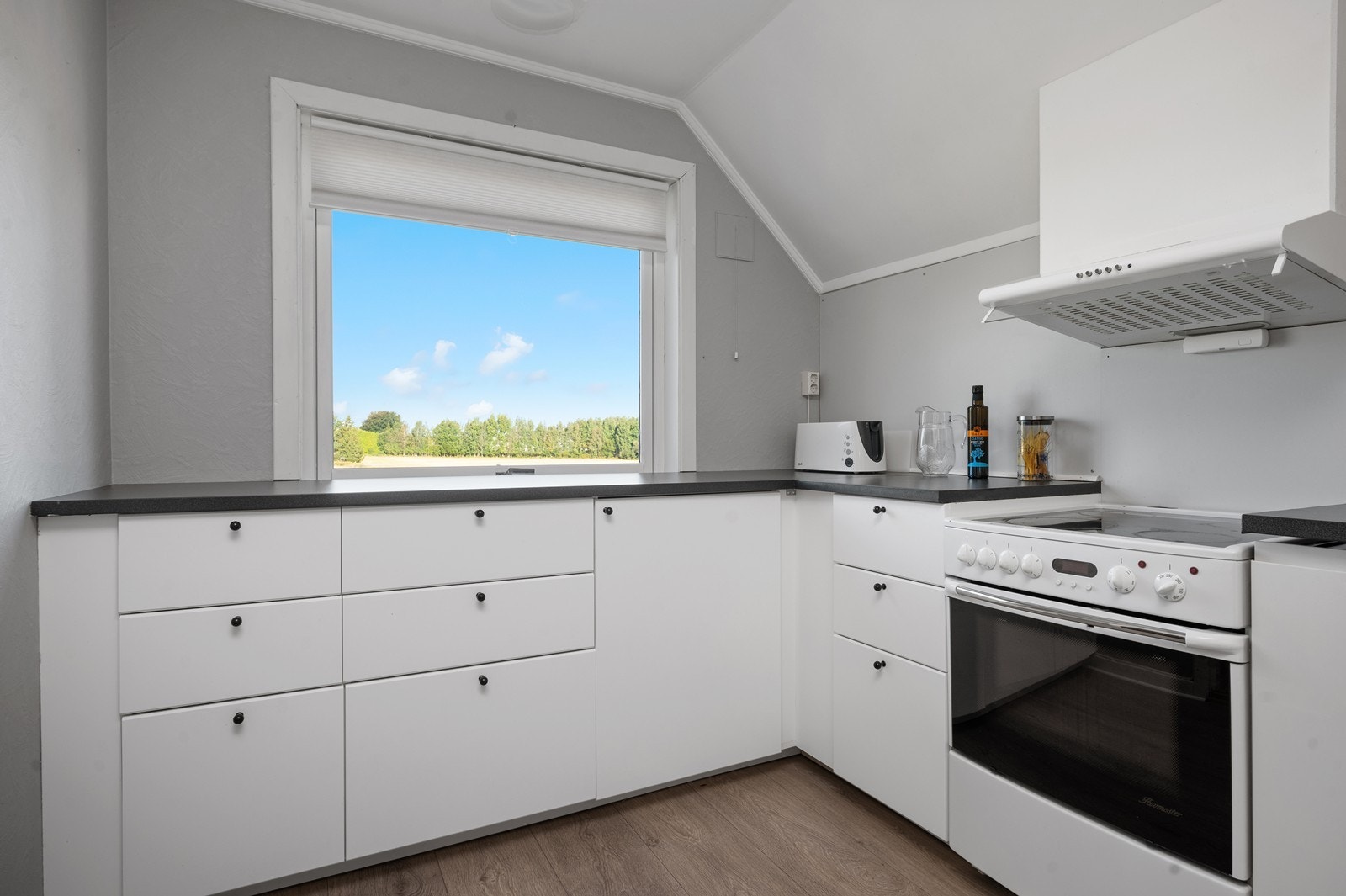 Kjøkken i andre etasje har laminat benkeplater og stort vindu over benken som gir godt med naturlig daglys Galleribilde