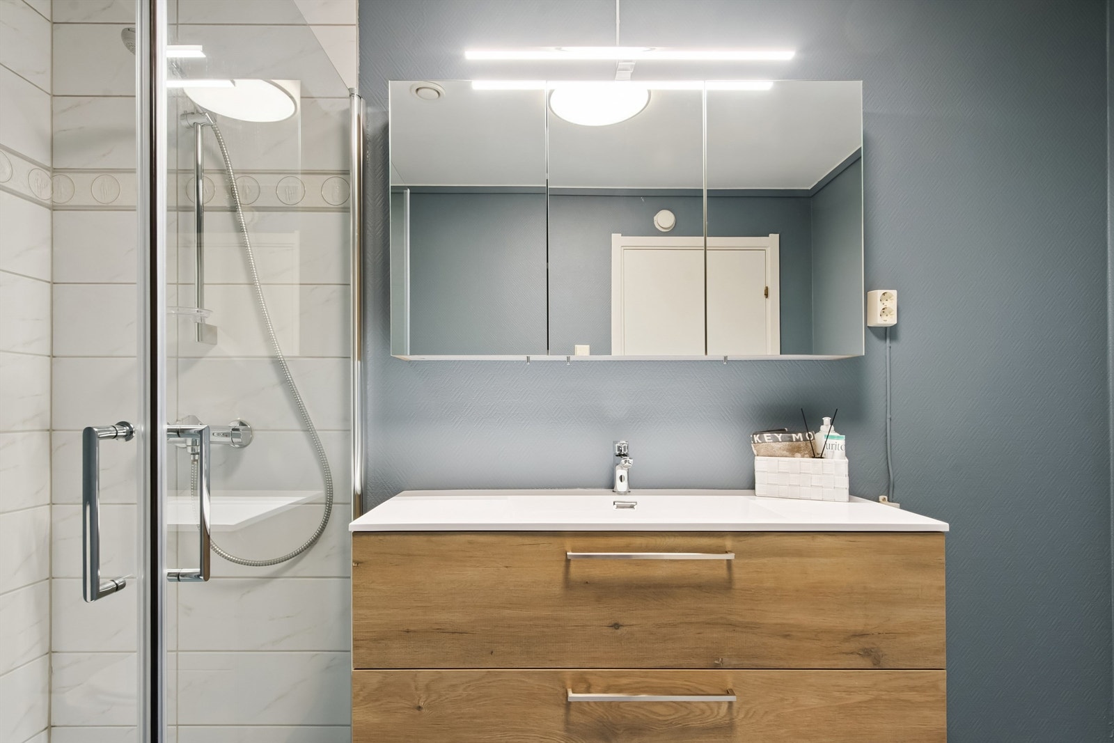 Baderomsinnredning med heldekkende servant og speilskap med integrert belysning. Galleribilde