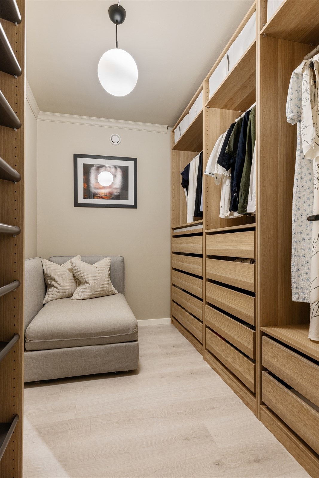 Romslig walk-in garderobe med praktiske garderobeløsninger som gir gode oppbevaringsmuligheter. Garderoben har adkomst fra entreen og fungerer som et ryddig og effektivt oppbevaringsrom Galleribilde