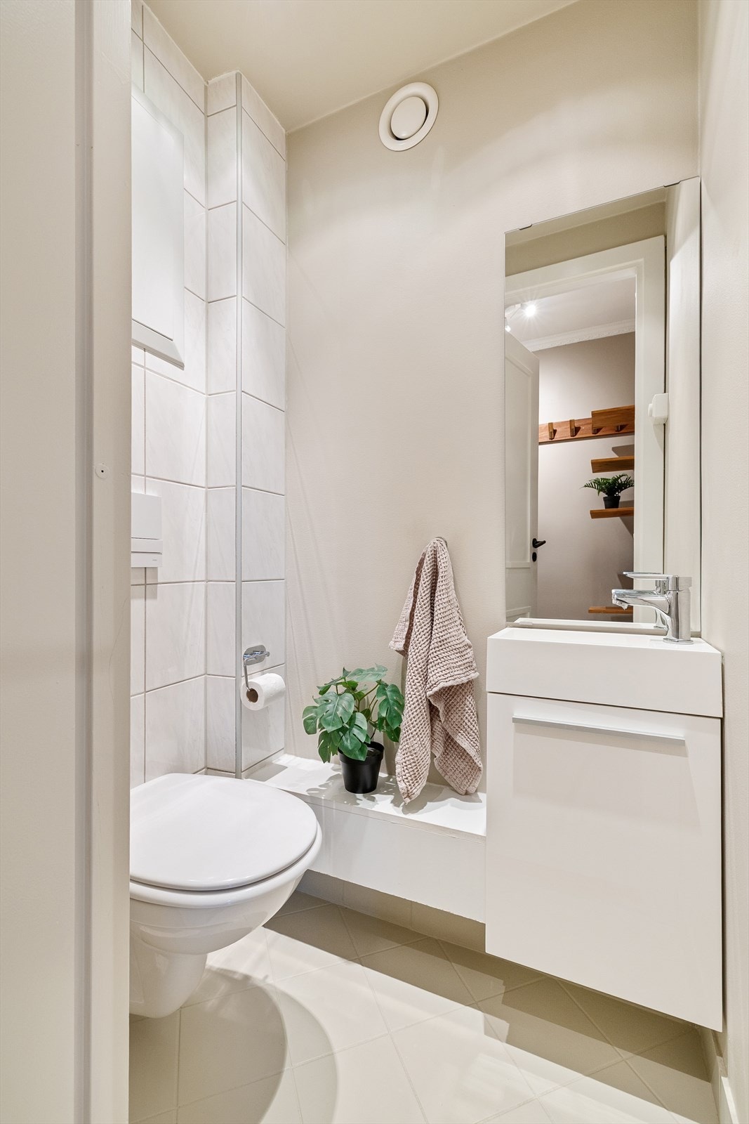 Toalettrom med flislagt gulv, flislagte- og malte veggflater, samt downlights i himling. Innredet med vegghengt toalett og en liten baderomsinnredning Galleribilde