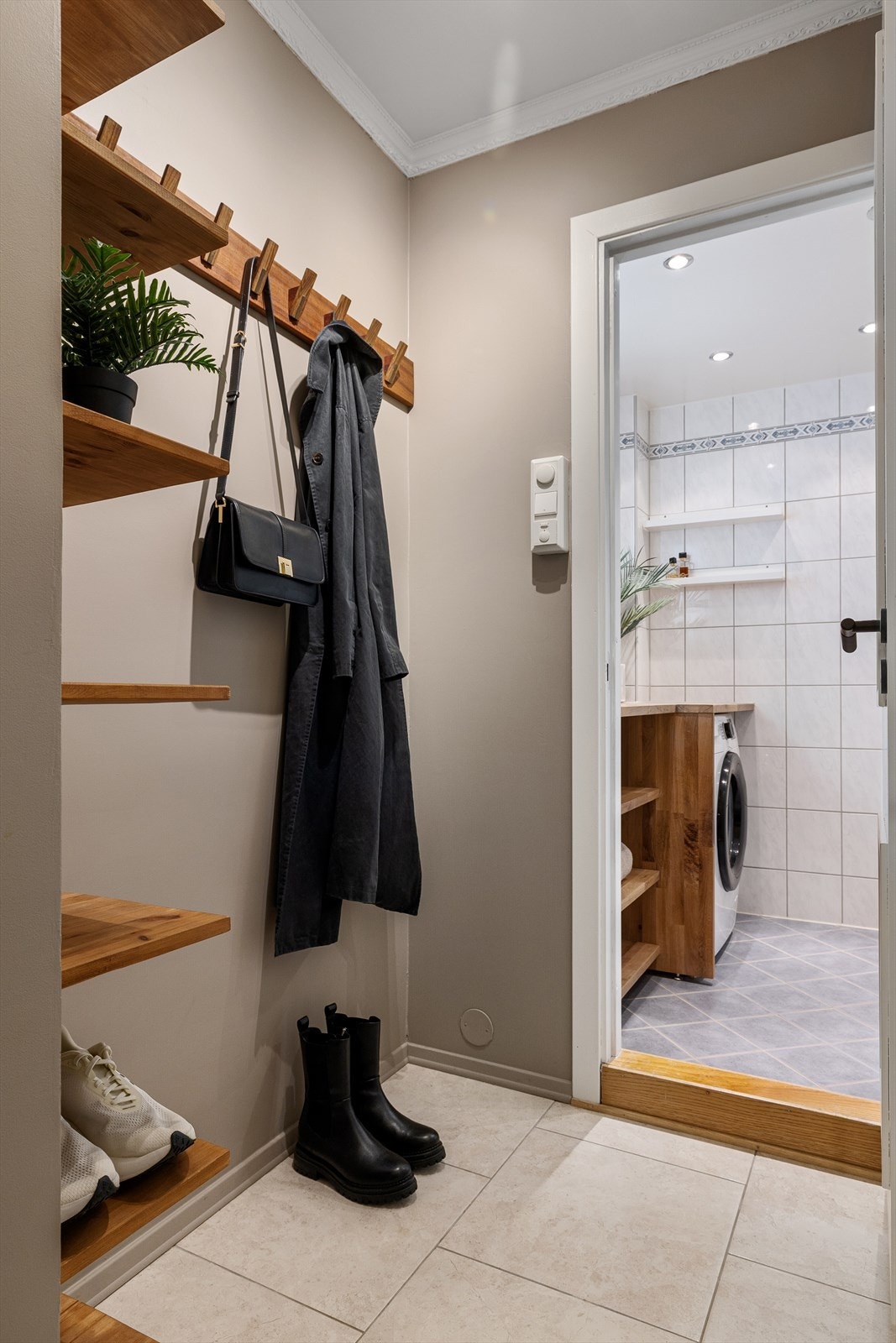 Mellomgangen mot badet er utstyrt med hyller og knagger, som gir praktisk plass til yttertøy og sko i en travel hverdag Galleribilde