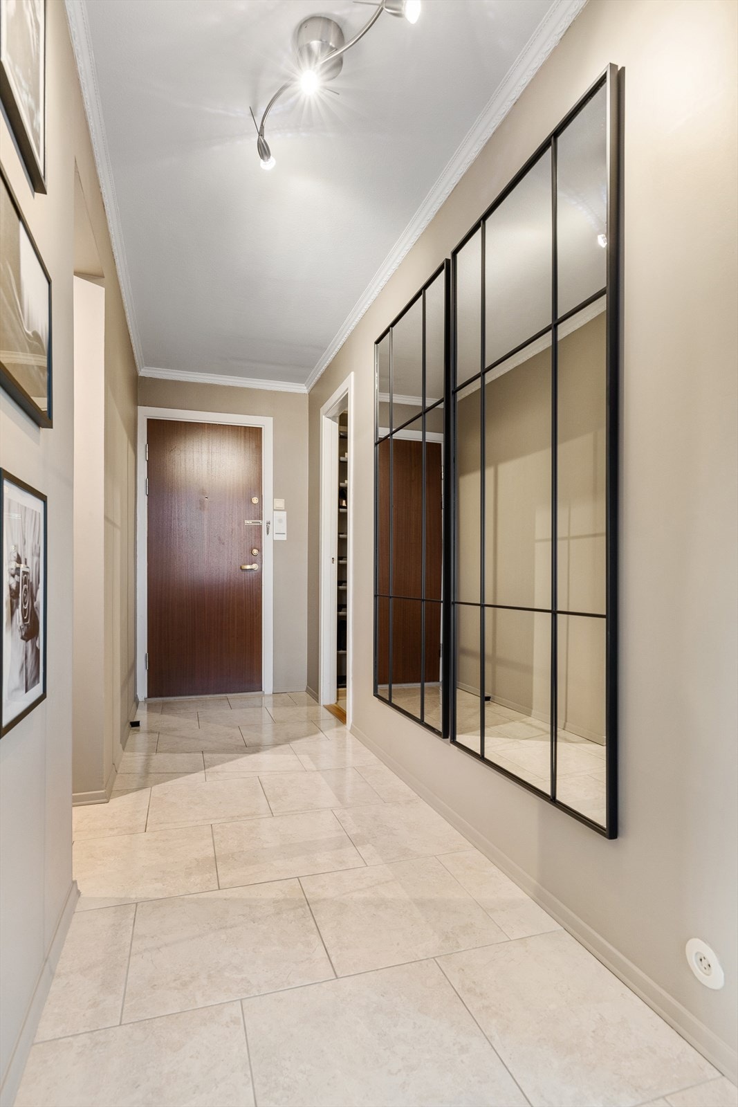 Stor entré/gang med flislagt gulv og veggflater malt i duse, tidsriktige fargetoner. Galleribilde