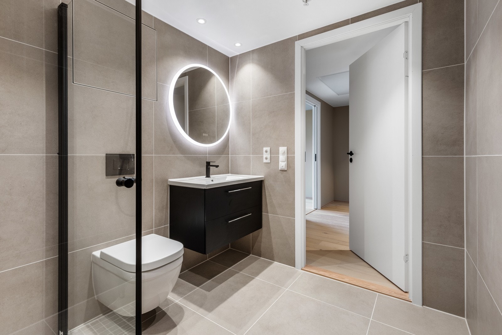 På gulv er det 60x60 flis og 60x30 cm på vegg i en behagelig grå/beige farge. I dusjsonen er det fliser på 5x5 cm i nedsenket sone. Galleribilde