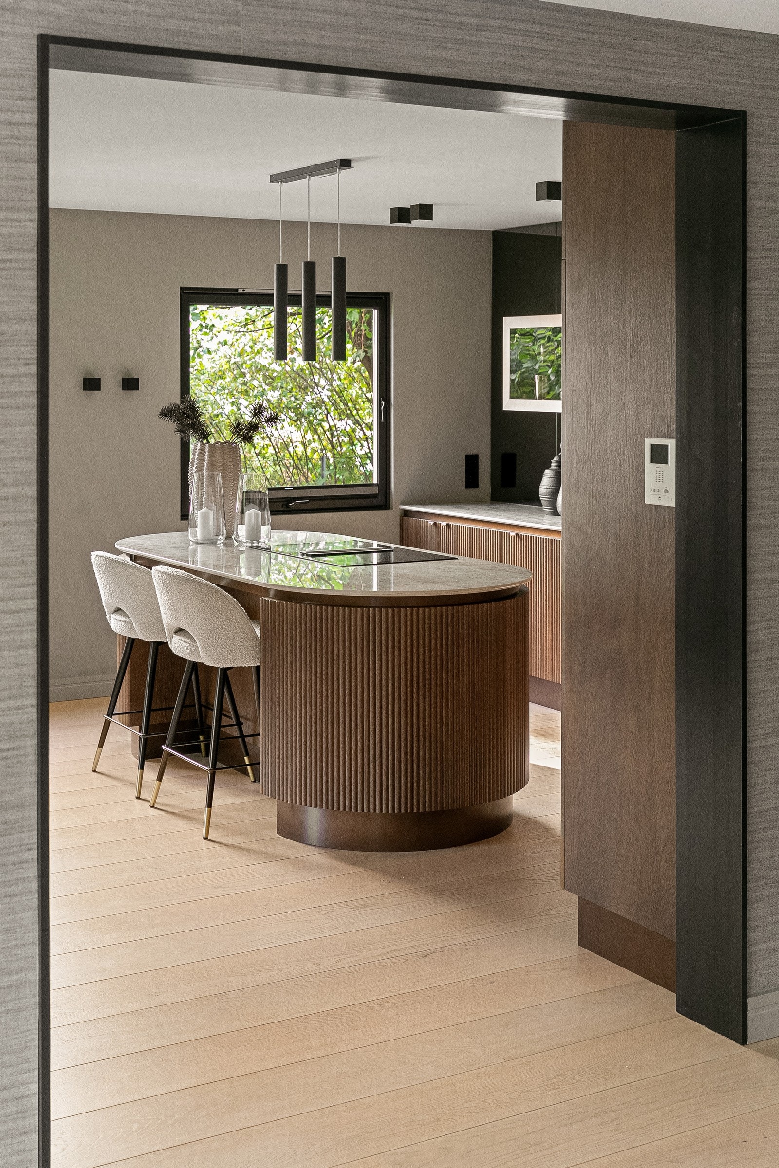 En oval kjøkkenøy med integrert ventilator og sitteplasser utgjør et naturlig samlingspunkt