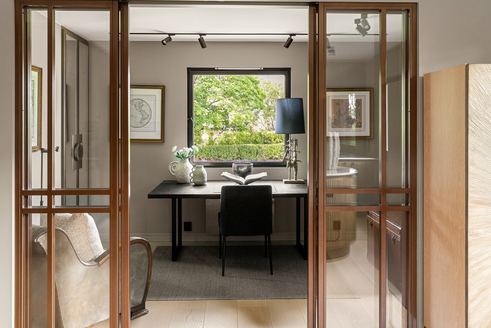 En stilren skyvedør i herdet glass leder inn til et kombinert kontor og bibliotek - alternativt et tredje soverom.