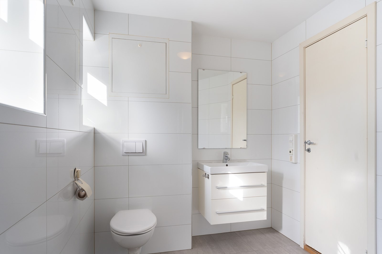 Helfliset bad/vaskerom som inneholder dusjnisje med dør, toalett, baderomsinnredning med heldekkende servant, veggskap, samt opplegg for vaskemaskin. Det er varmekabel i gulvet, samt elektrisk avtrekksvifte. Galleribilde