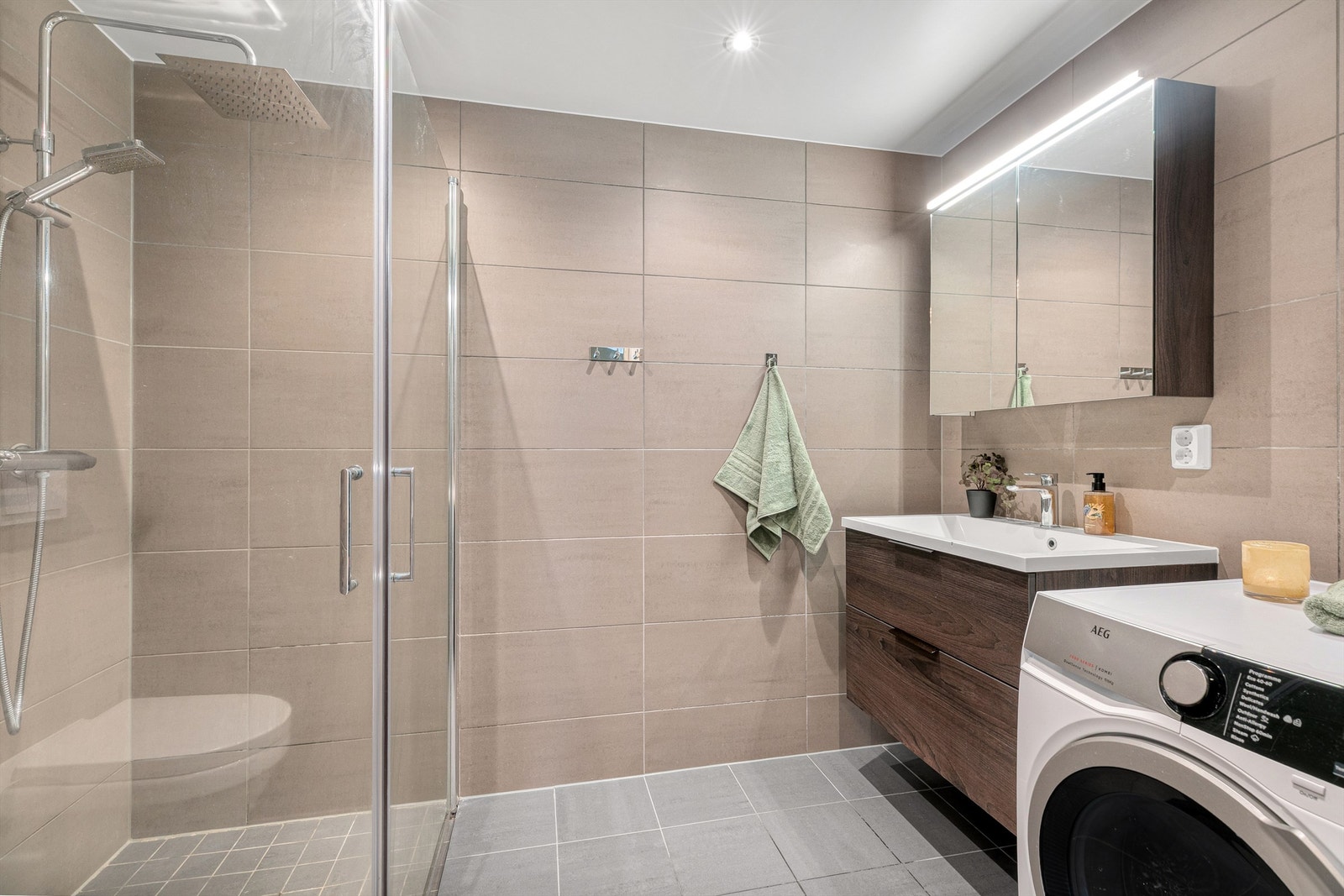 Malt himlingsflate med downlights. Vegghengt servantskap med heldekkende servant og ett-greps armatur. Speilskap med lys over servant. Dusjnisje med innfellbare glassdører. Galleribilde