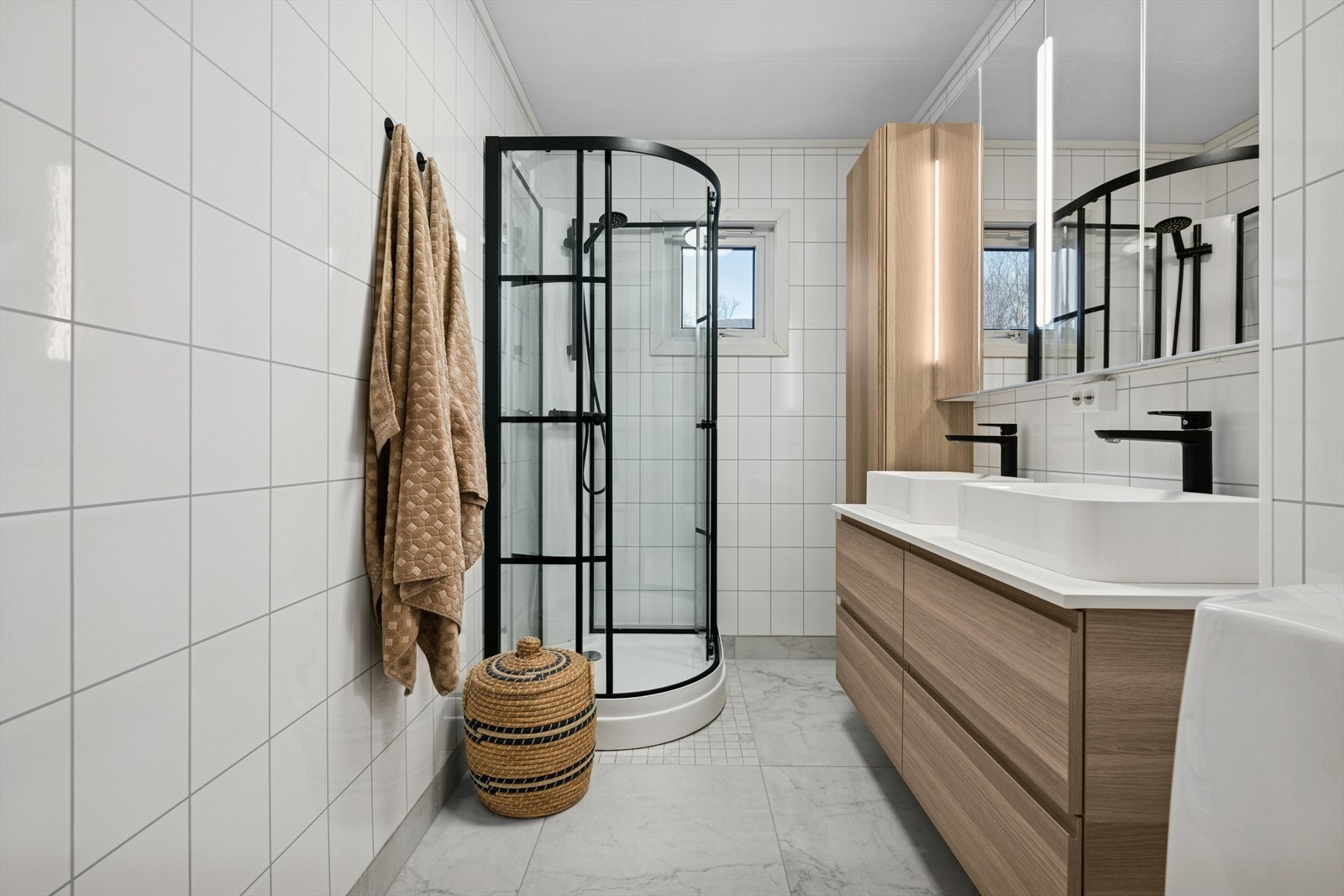 Pen flislagt bad med dusjkabinett og en stilfull og romslig baderomsinnredning. Galleribilde