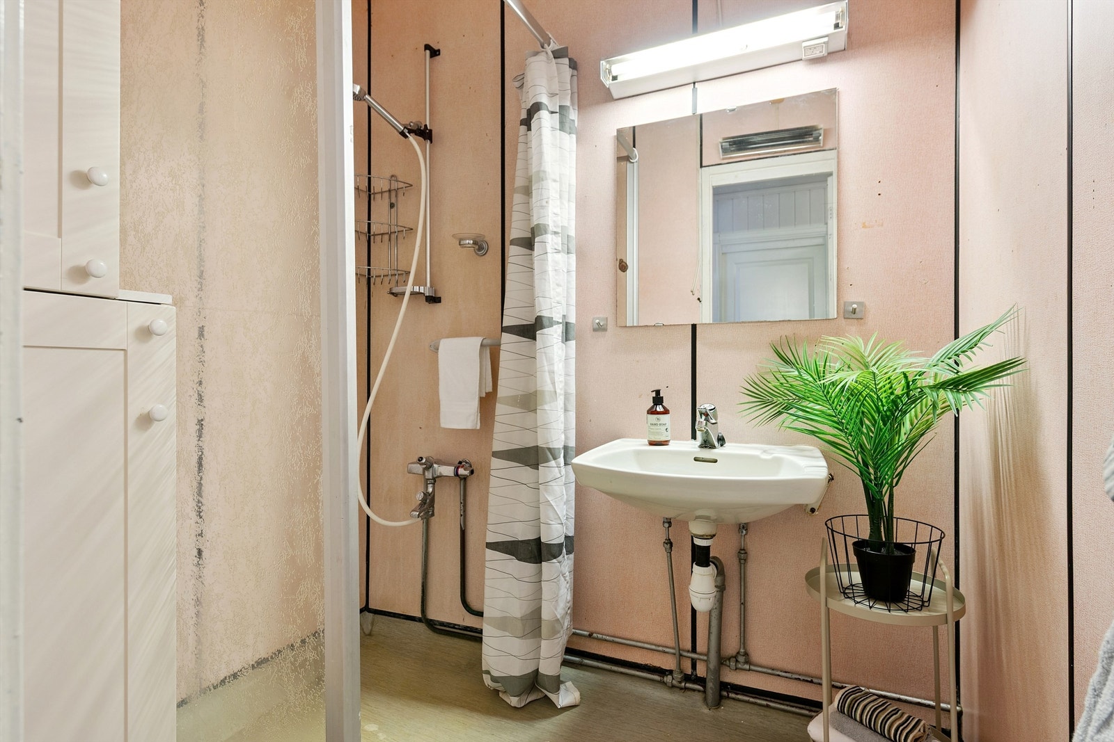 Badet er utstyrt med dusj og servant med oppbevaringsplass. Galleribilde