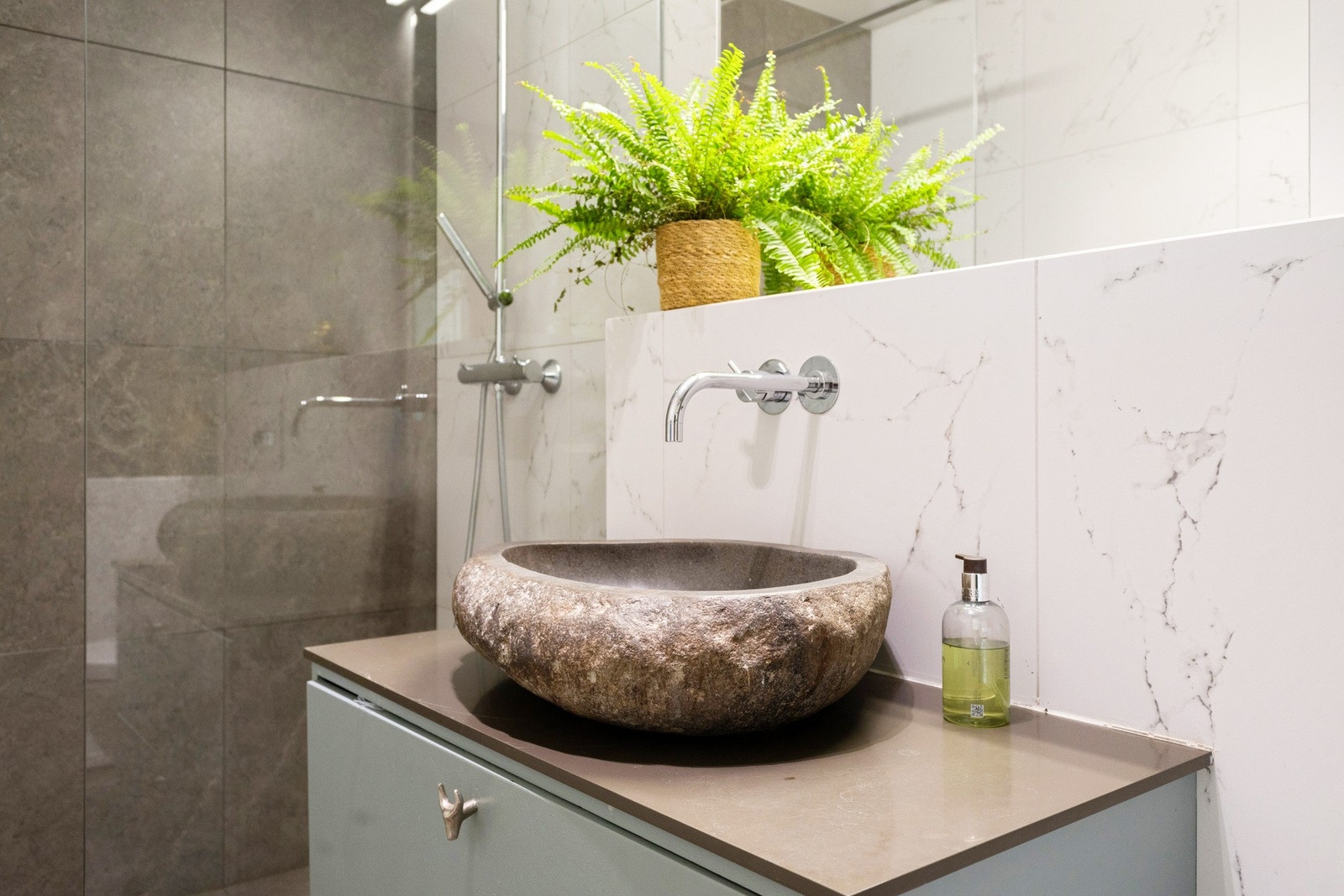 Badet har servantskap med skuffer, ovenpåliggende servant av stein fra Bali med Vola armatur, samt speil med overbelysning på vegg over servant. Galleribilde