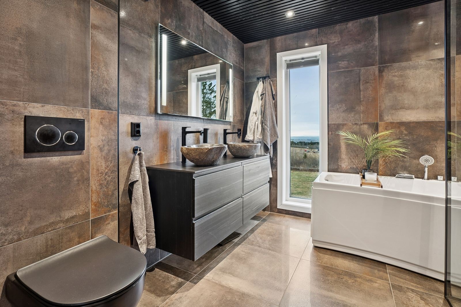 Overflater med moderne, store fliser, varme i gulv og downlights innfelt i panelt himling. Galleribilde