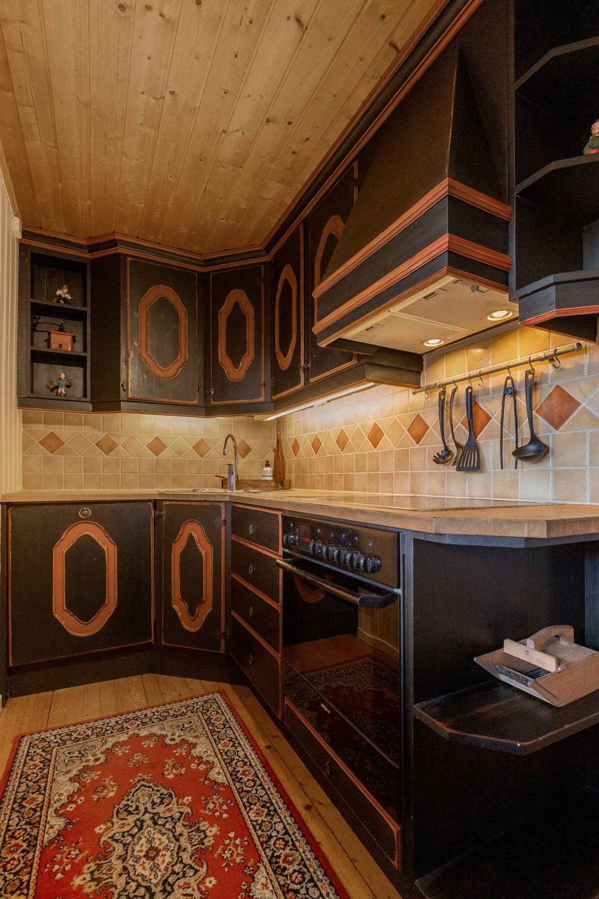 Plassbygd, heltre innredning i malt utførelse. Profilerte fronter, noen av kjøkkendørene har malt motiv som setter særpreg Galleribilde