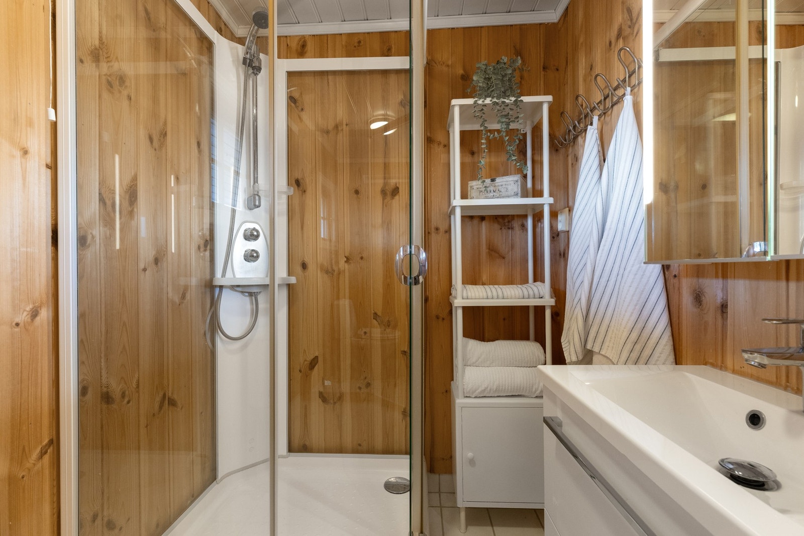 Badet har flislagt gulv og panel på veggene Galleribilde