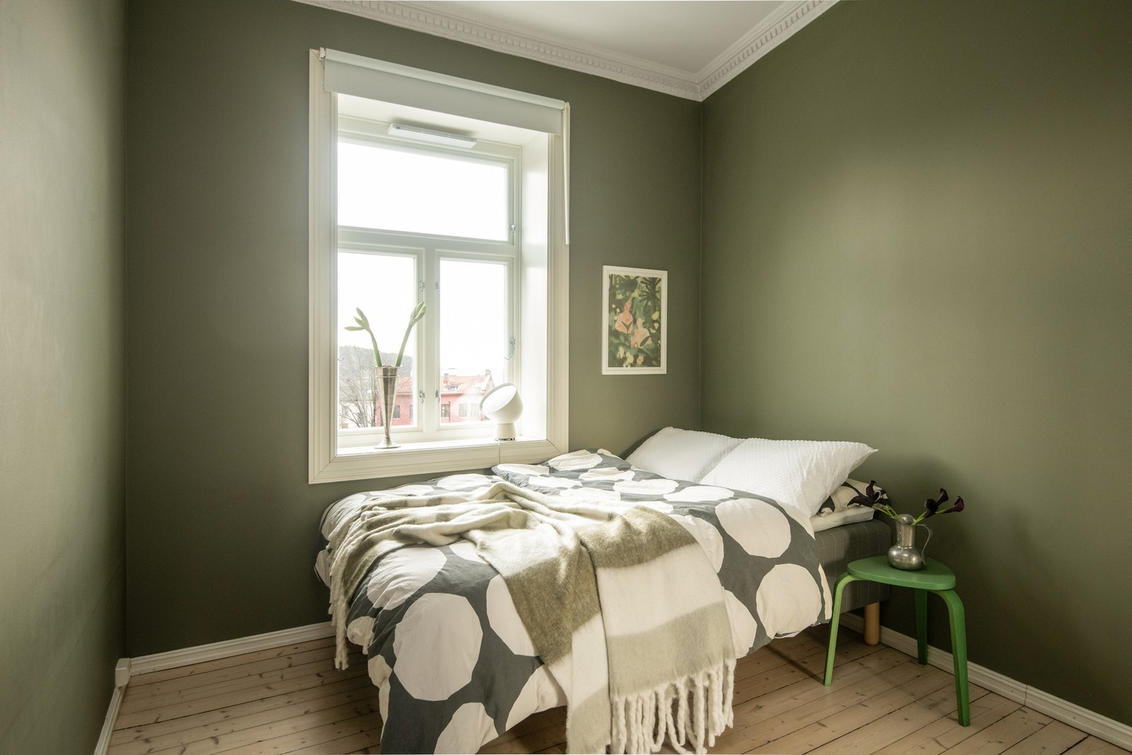 Soverommet fremstår som et behagelig og innbydende rom, hvor veggene er malt i en dempet olivengrønn nyanse som skaper en lun og rolig atmosfære. Galleribilde