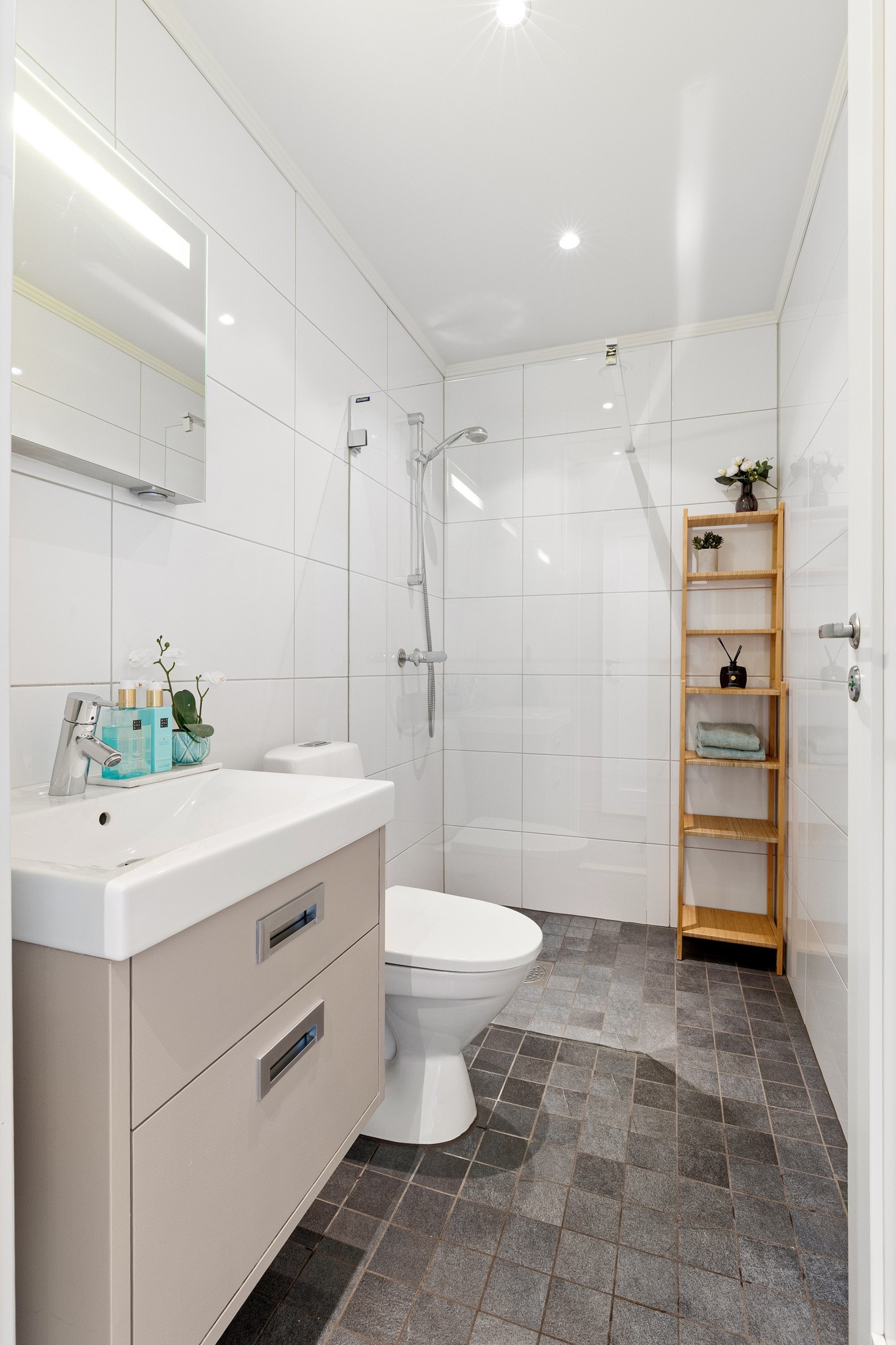 Badet i første etasje har et pent uttrykk med fliser på både vegger og gulv, varmekabler og innfelt downlights. Galleribilde