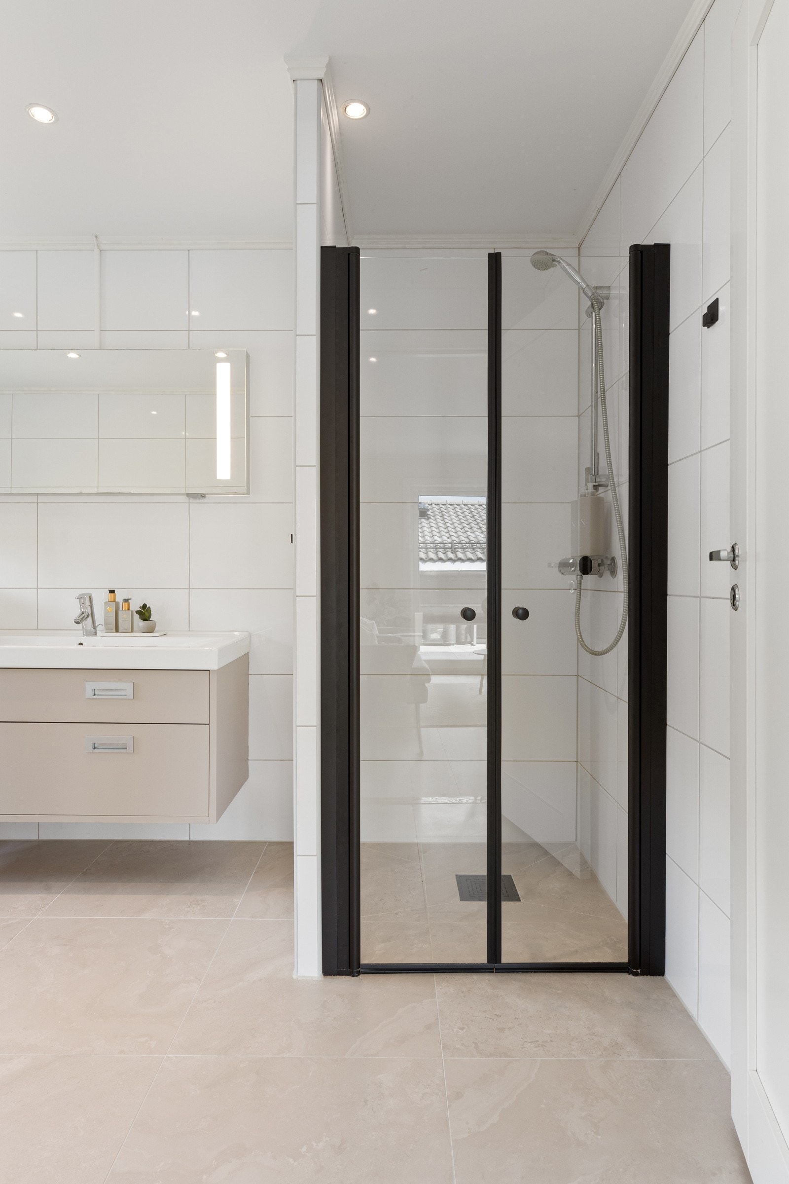 Innredningen besår av servantinnredning, speil på vegg over servant, vegghengt toalett, innmurt badekar og dusjhjørne med svingbare glassdører. Galleribilde