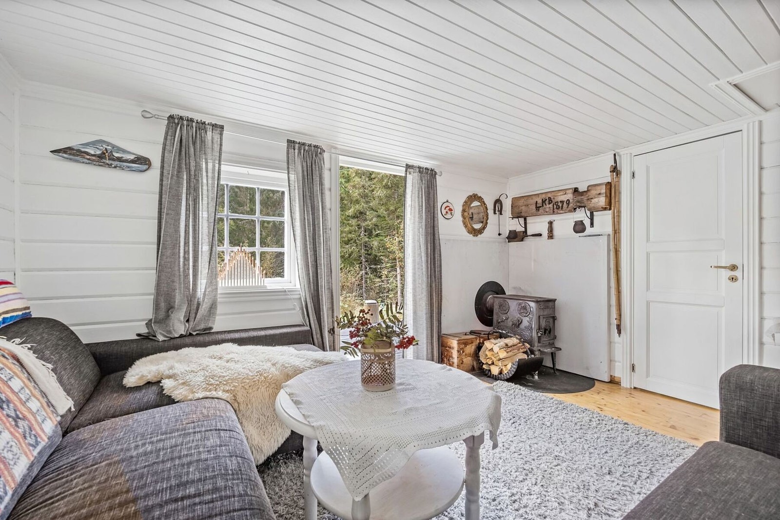 Hjemmekoselig atmosfære med peisovn, myke tekstiler og store vinduer som slipper inn naturlig lys fra de naturskjønne omgivelsene. Galleribilde