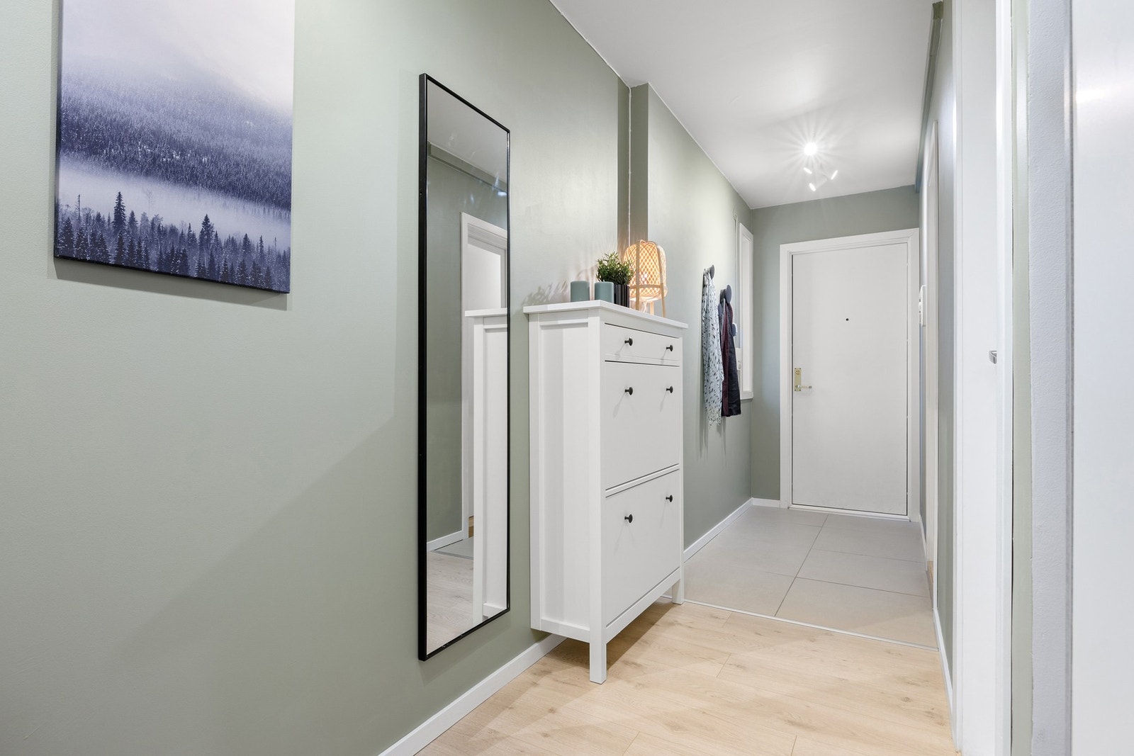 Gang sett mot ytterdør. Moderne 60x60-flis i yttergang. Sikringsskap med automatsikringer rett utenfor døren. Galleribilde