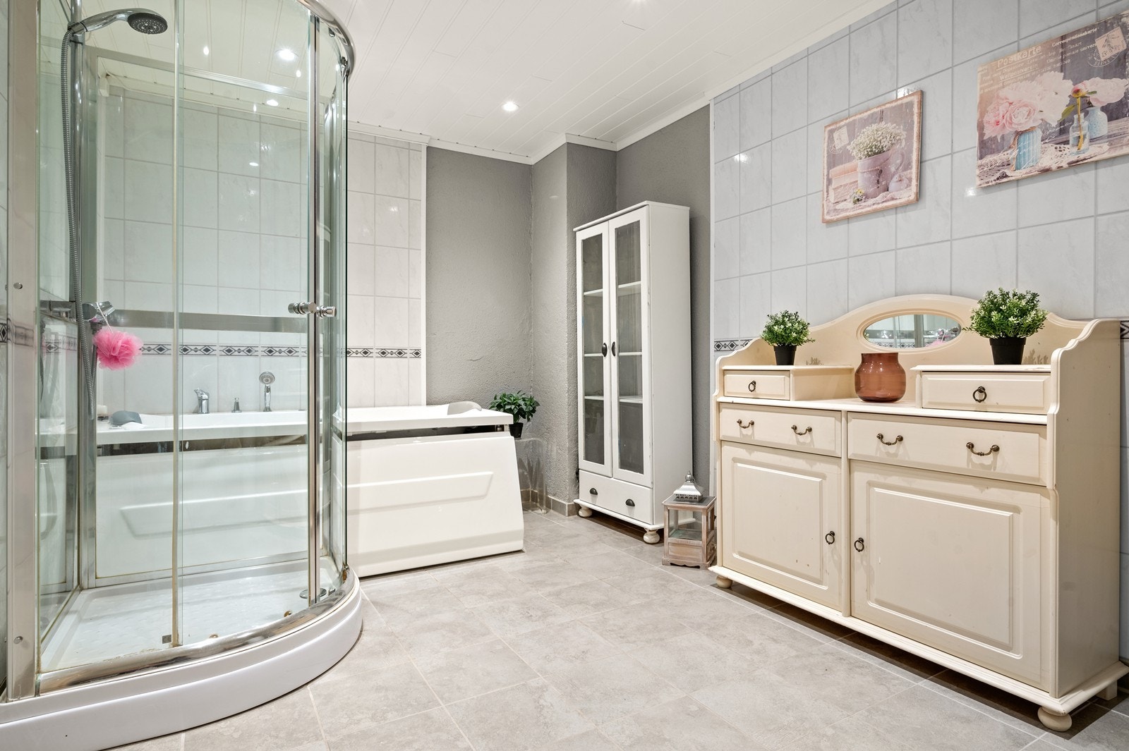 Romslig baderom, pusset opp i 2012 i flg. en tidligere takstrapport. På gulvet er det fliser med elektriske varmekabler under. På veggene er det baderomplater og malt mur. I taket er det malt mdf-panel med innfelte spotter, i fra 2022 Galleribilde