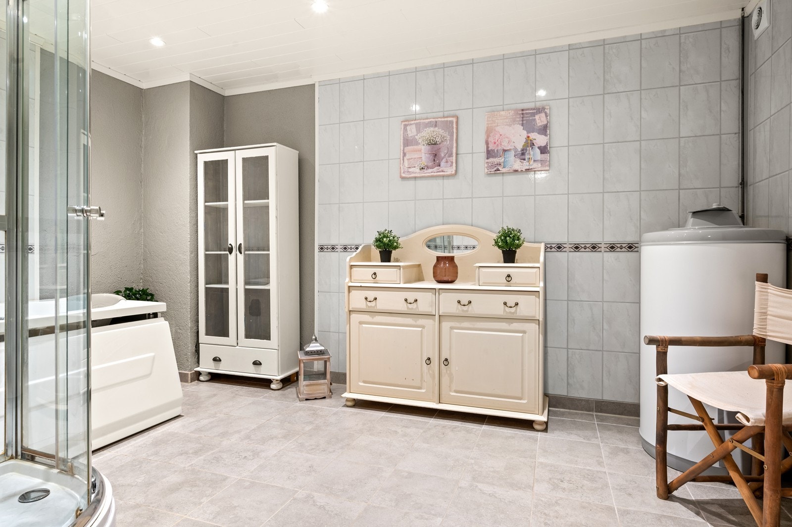 Rommet er utstyrt med badekar og dusjkabinett. Det er plass til diverse lagringsmøbler, i tillegg er varmtvannstanken plassert her Galleribilde