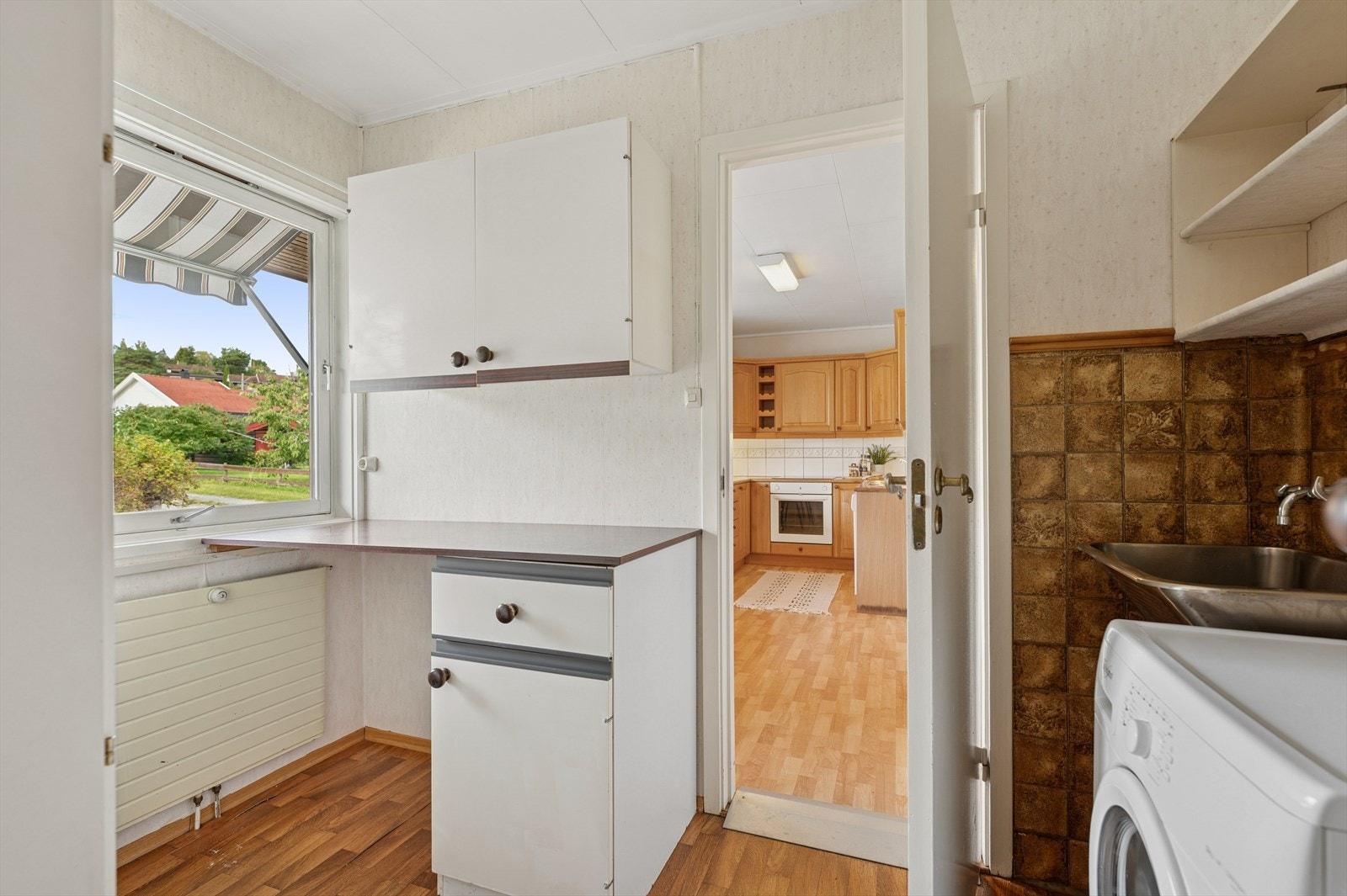 Praktisk vaskerom med opplegg for vaskemaskin og utslagsvask på vegg. Galleribilde