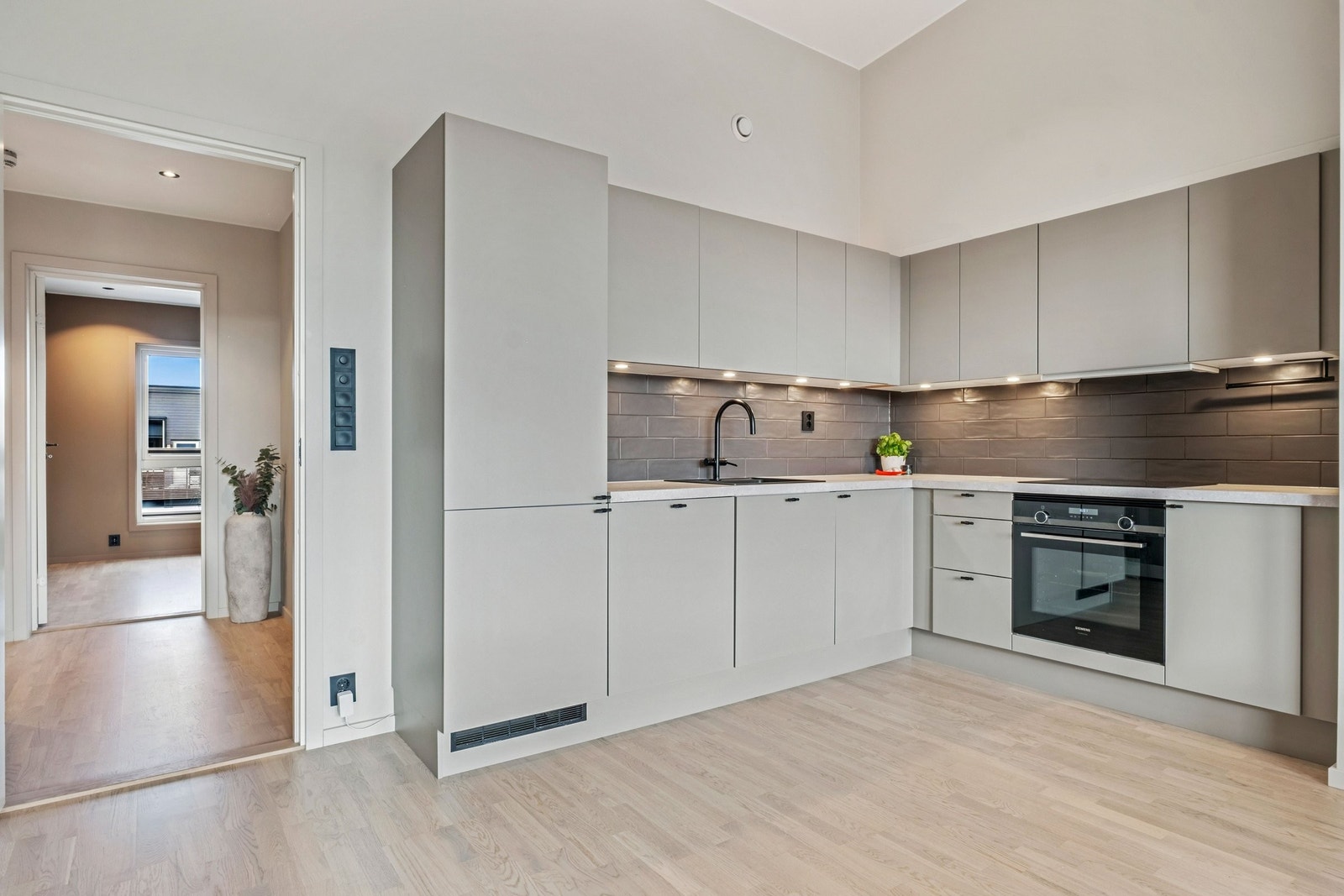 Påkostet kjøkken fra HTH med integrerte hvitevarer og sorte detaljer i behagelige toner. Galleribilde